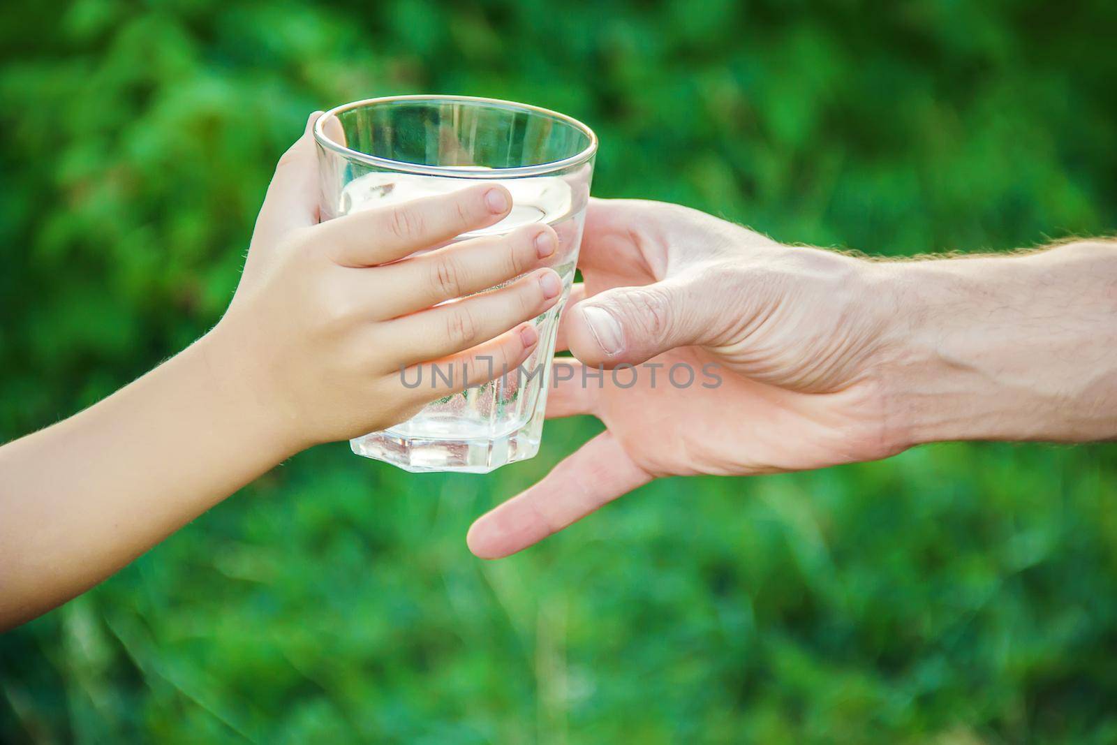 The father gives the child a glass of water. Selective focus.