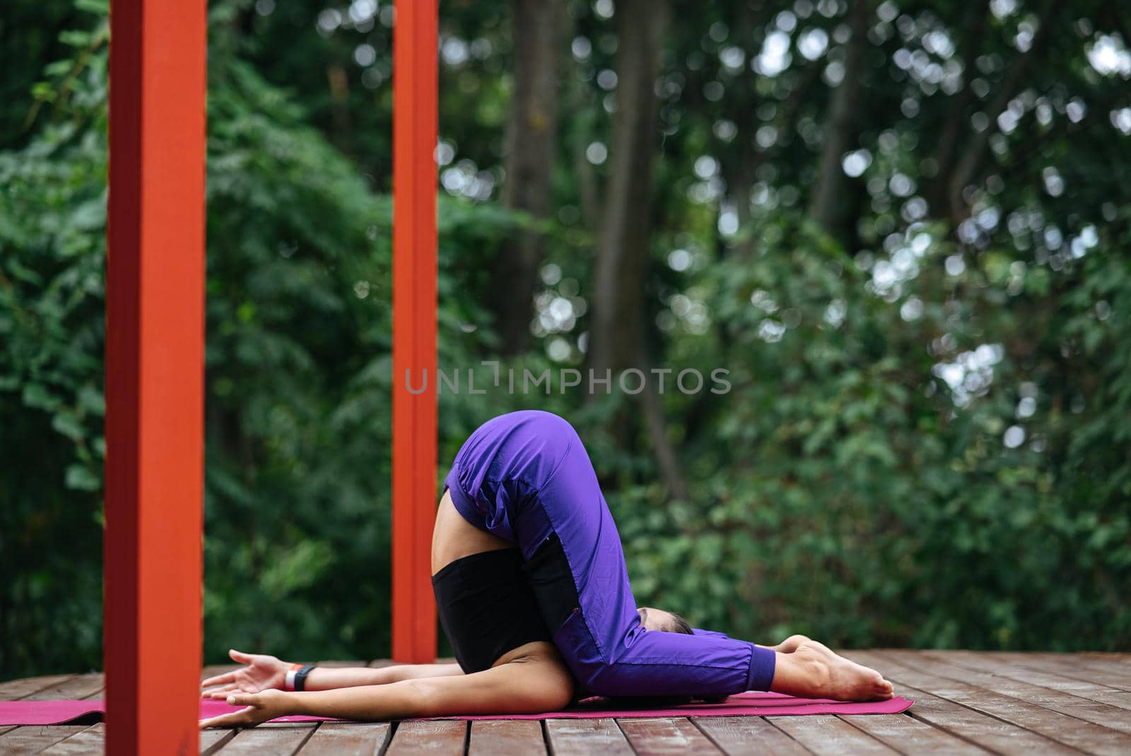 A young woman in doing yoga in the yard on the veranda