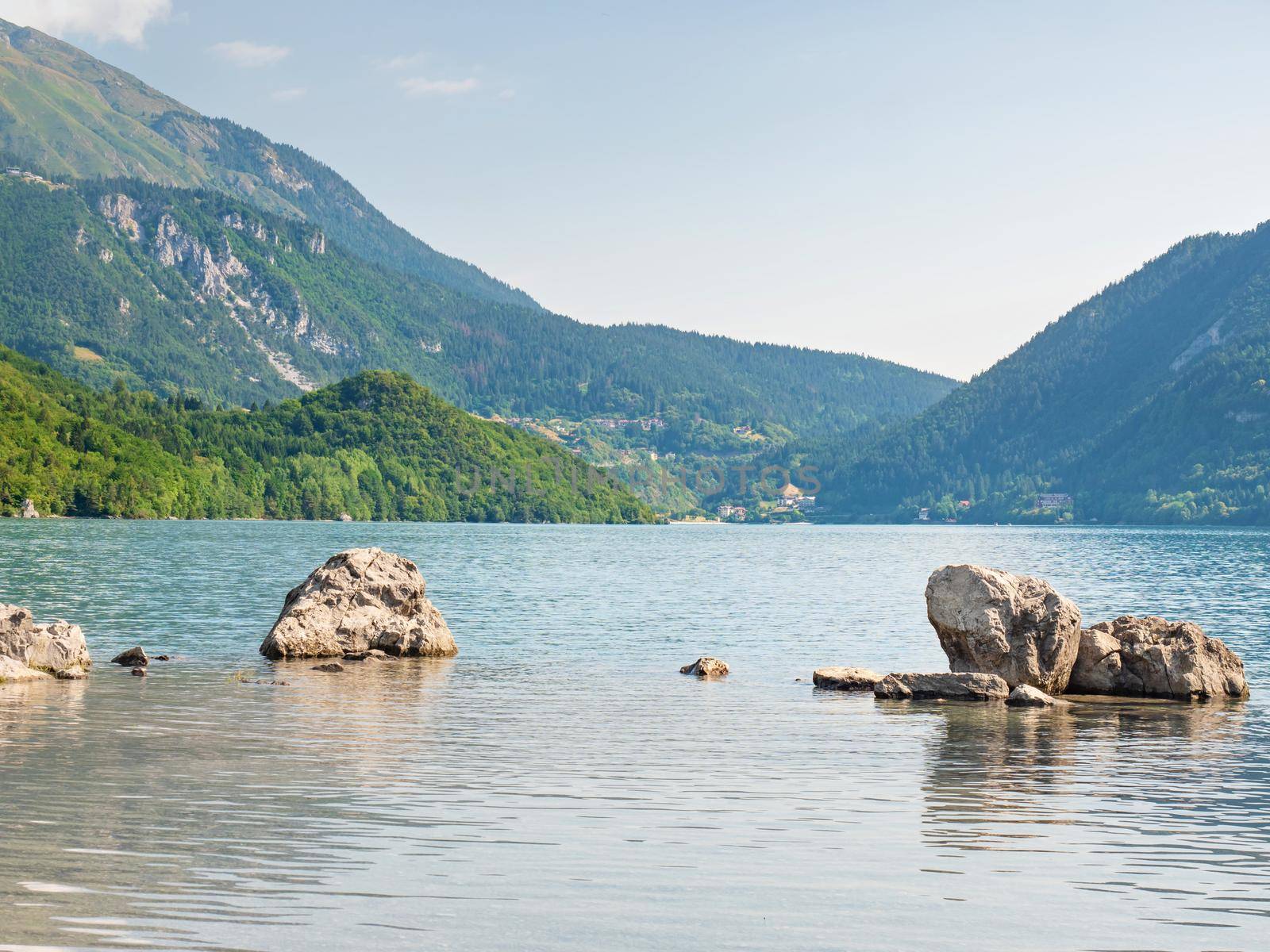 Stones stack on shore of blue green water of mountain lake Molveno.  by rdonar2