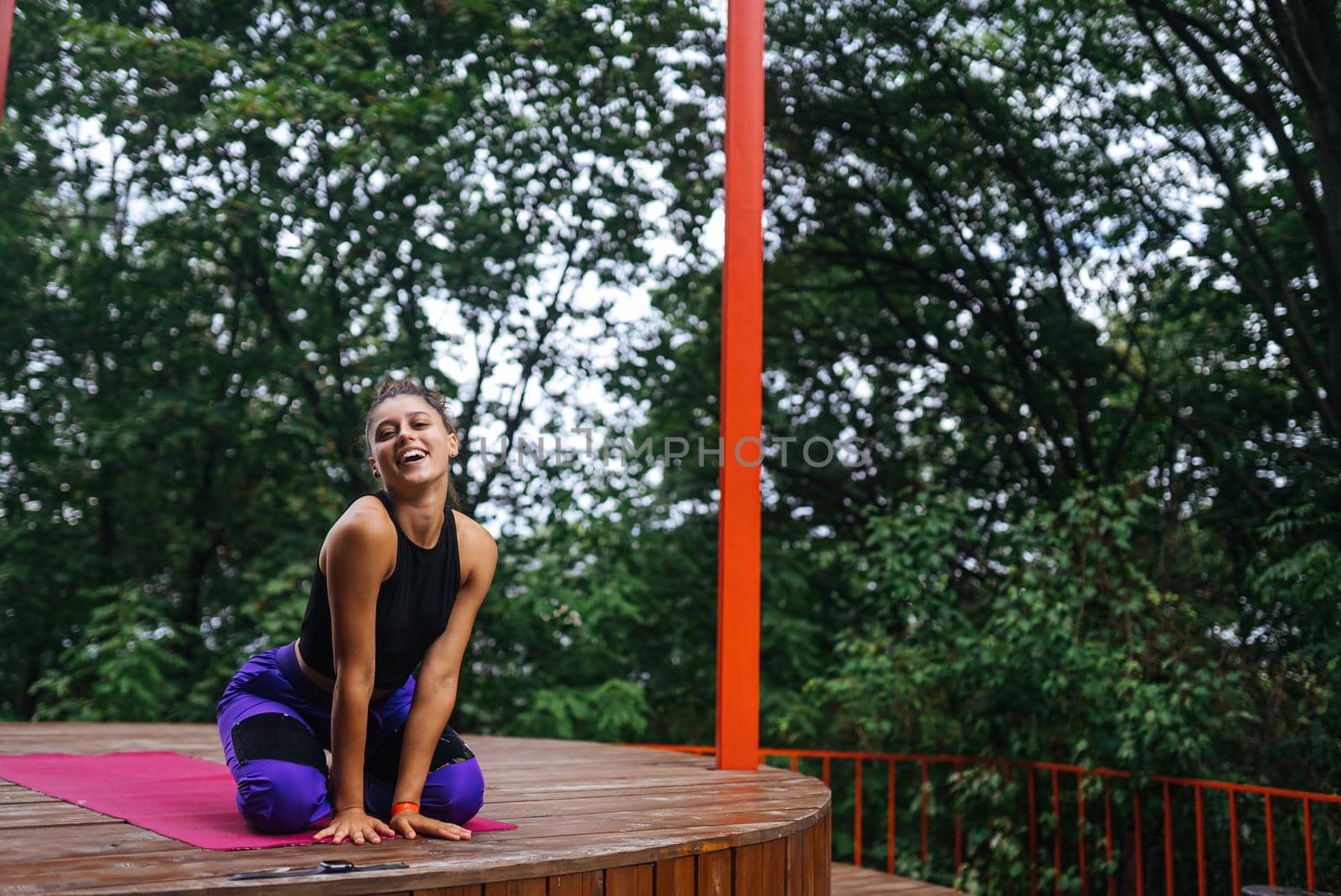 Young woman sitting on the wooden floor on the veranda after training