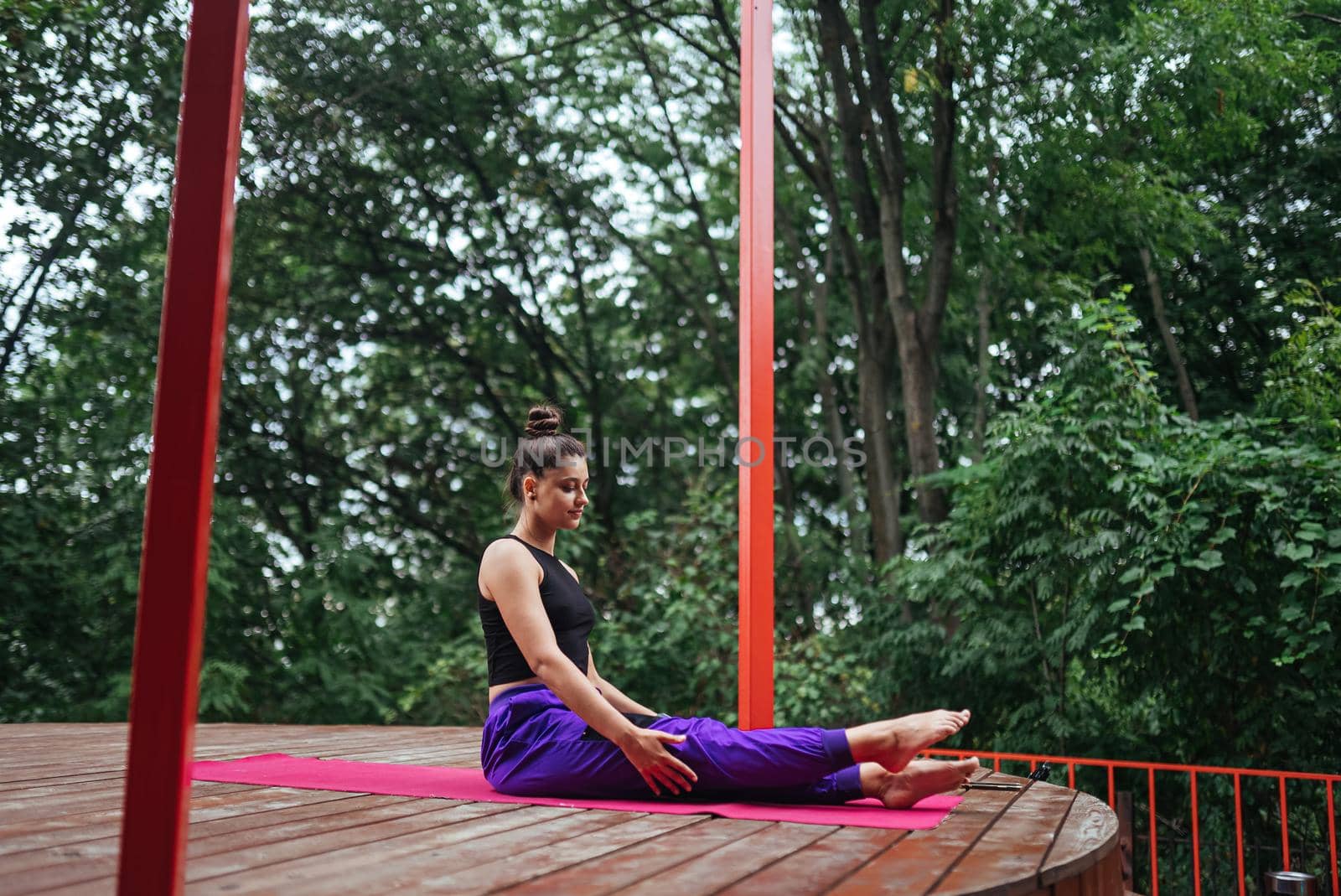 A young woman in doing yoga in the yard on the veranda