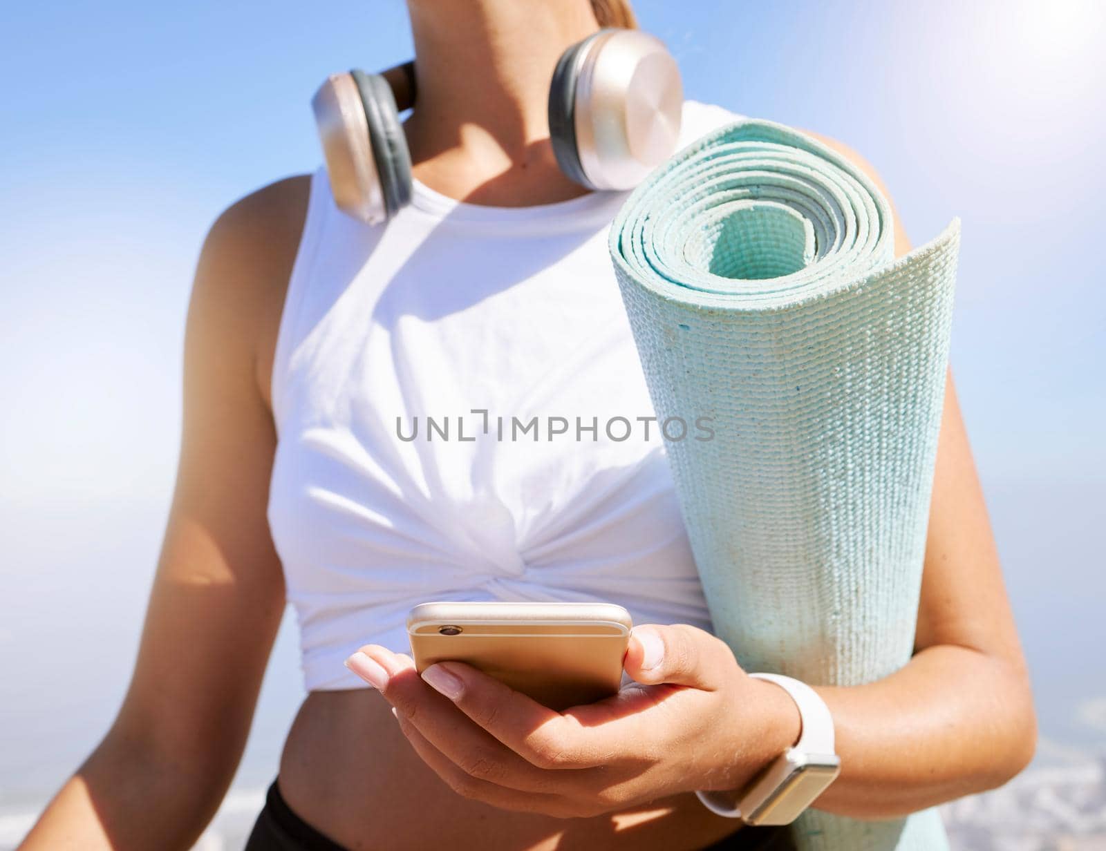 Fitness, yoga and woman on a phone in nature, texting and listening to music before summer outdoor workout. Radio, podcast and wellness exercise with female relax while searching for online playlist.