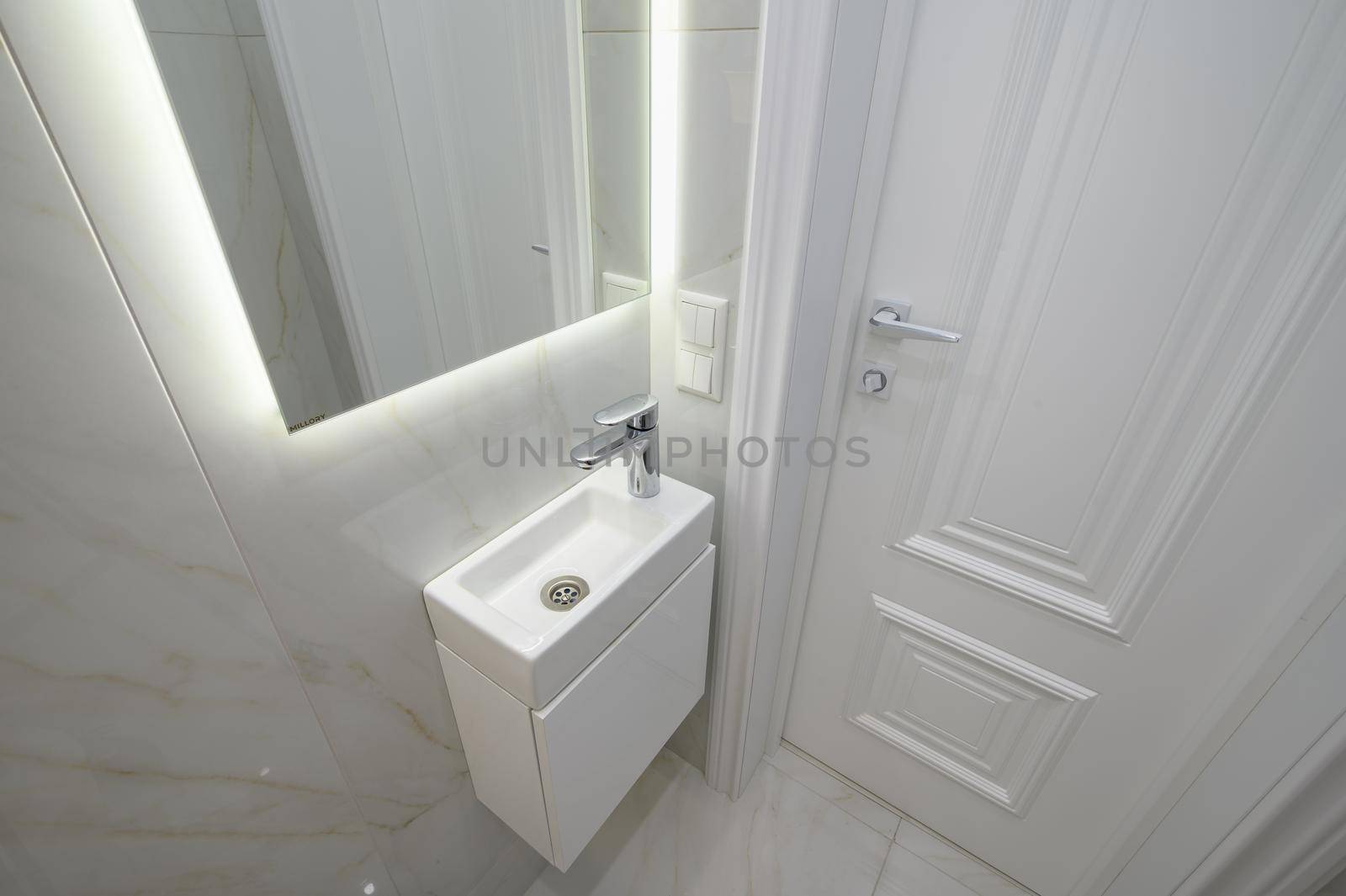 Small white hand wash sink and vanity mirror in bathroom interior