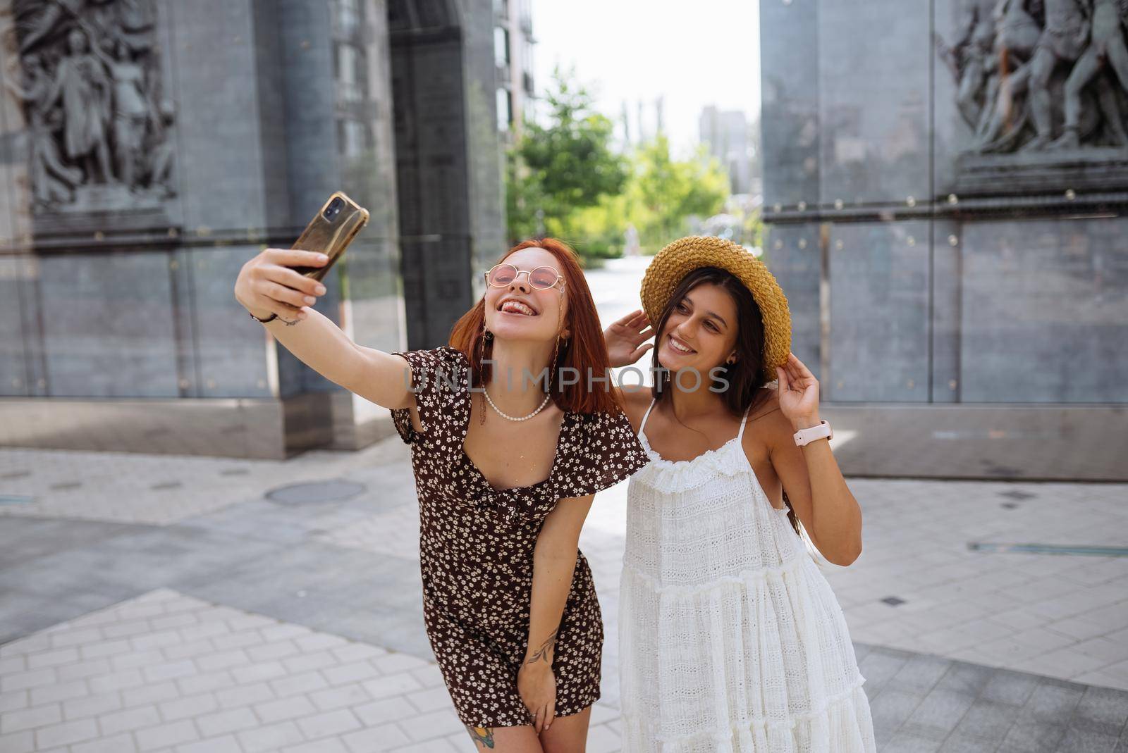 Two joyful cheerful girls taking a selfie outdoors