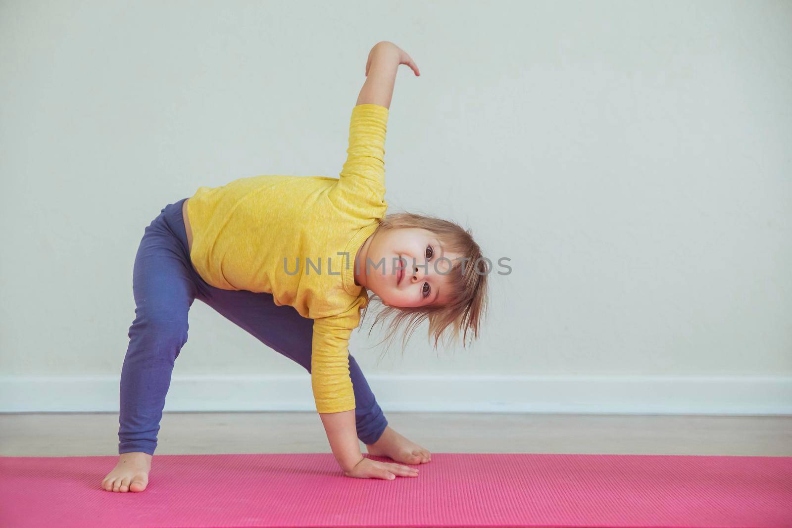 Charming baby doing yoga at home. Place for text.