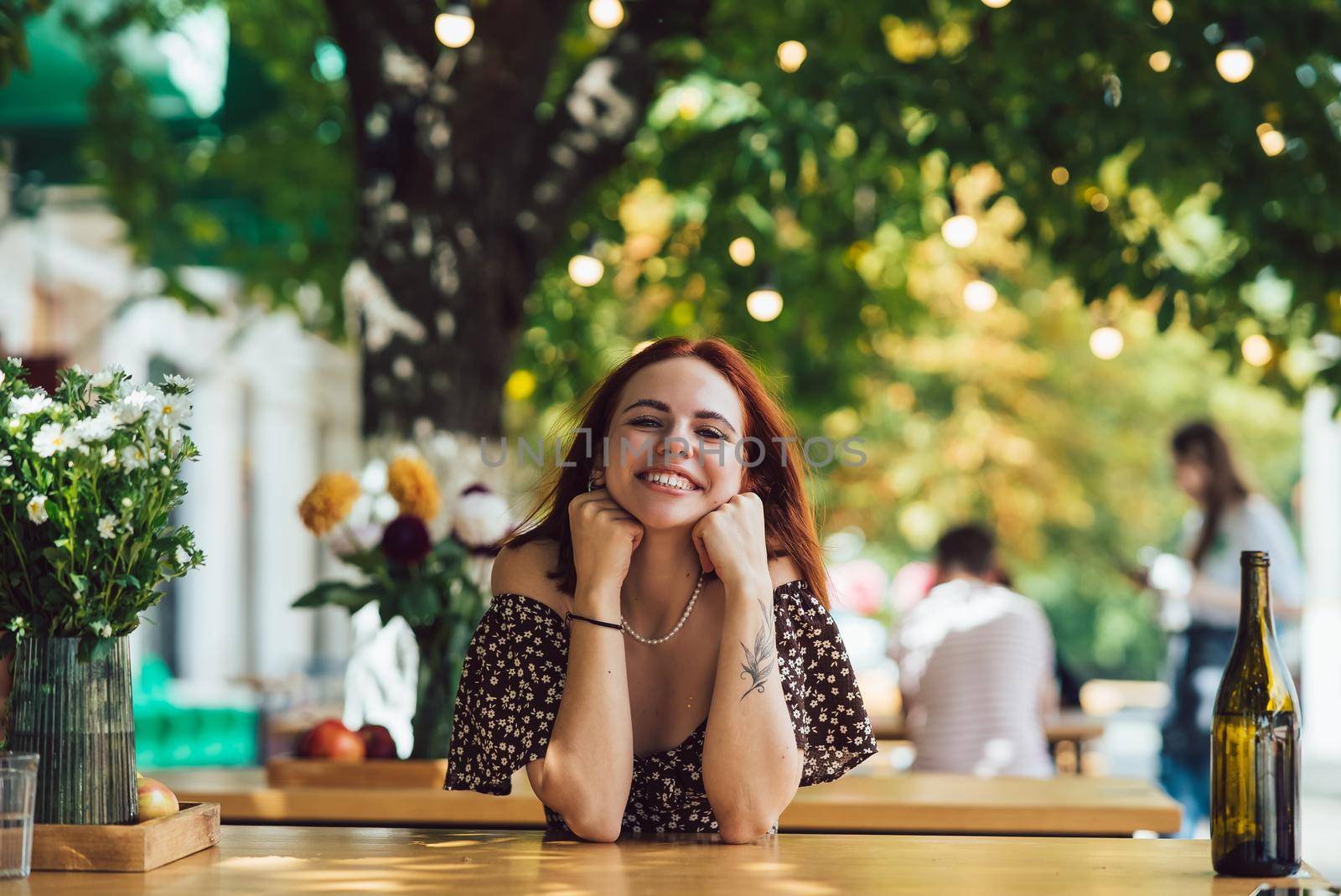 Close-up portrait of two female friends laughing drinking coffee on terrace at summer street cafe on background buildings