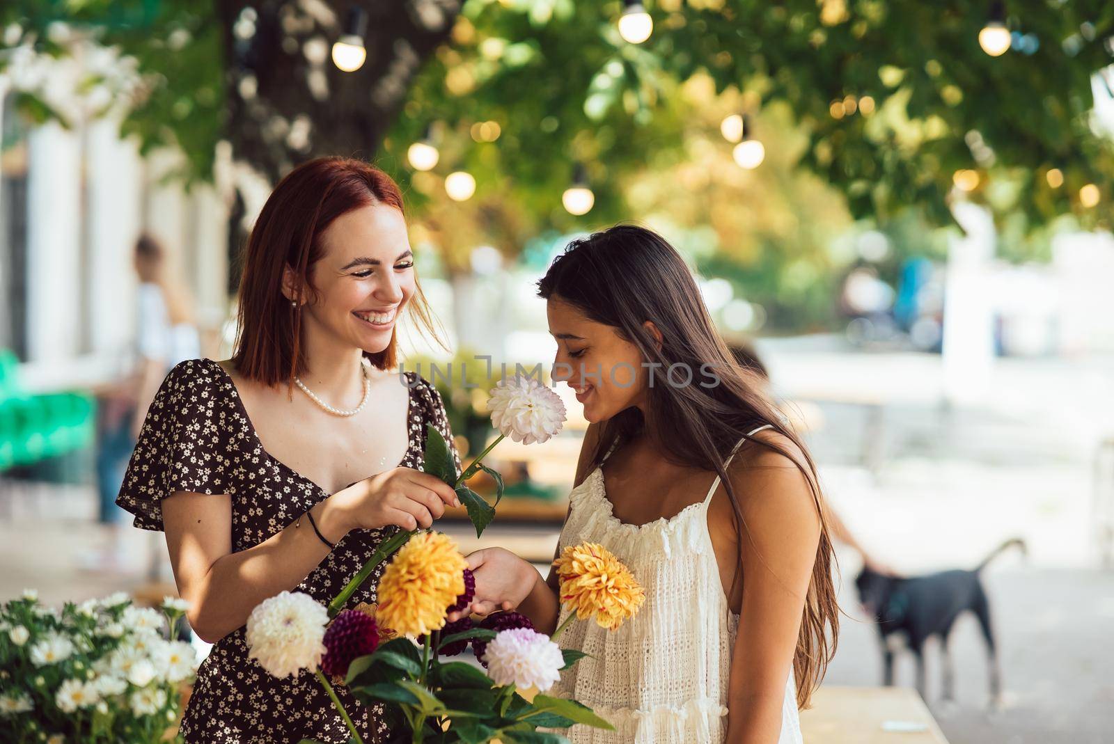 Two young women take orders and make up a beautiful festive bouquet. Floristry and making bouquets at the street caffe. Small business.
