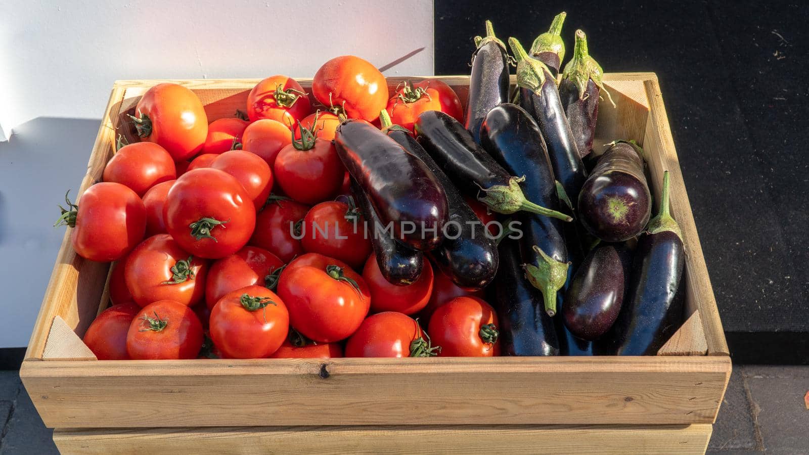 Tomatoes and eggplants, vegetables in a wooden box. High quality photo