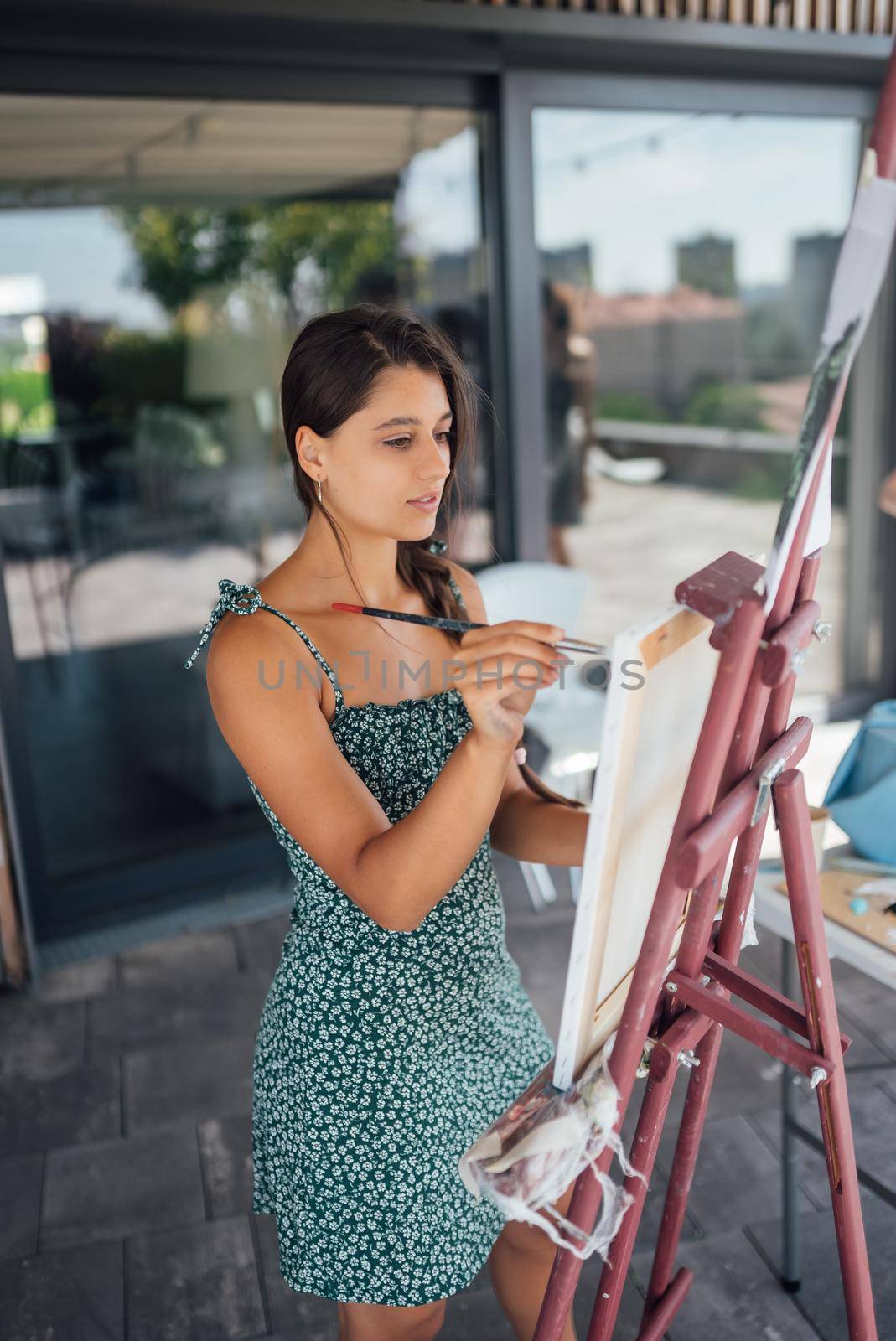 Beautiful woman artist drawing her picture on canvas with oil colors in studio