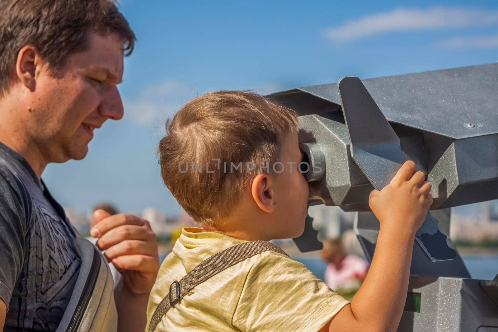 The boy looks through binoculars from the observation deck. Journey. Tourism