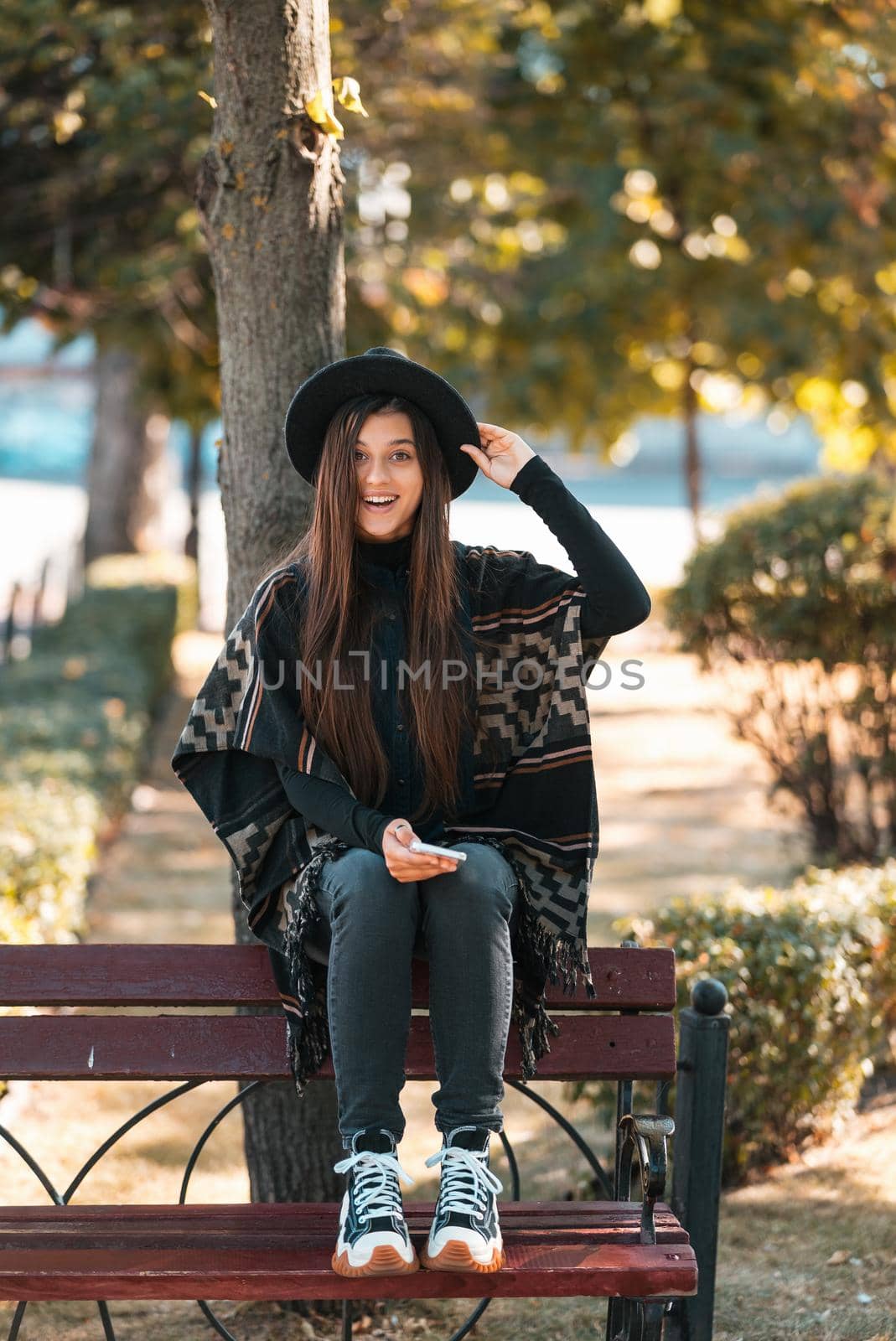 Young woman on a bench in the autumn park. People, freedom, lifestyle, travel and vacations concept.