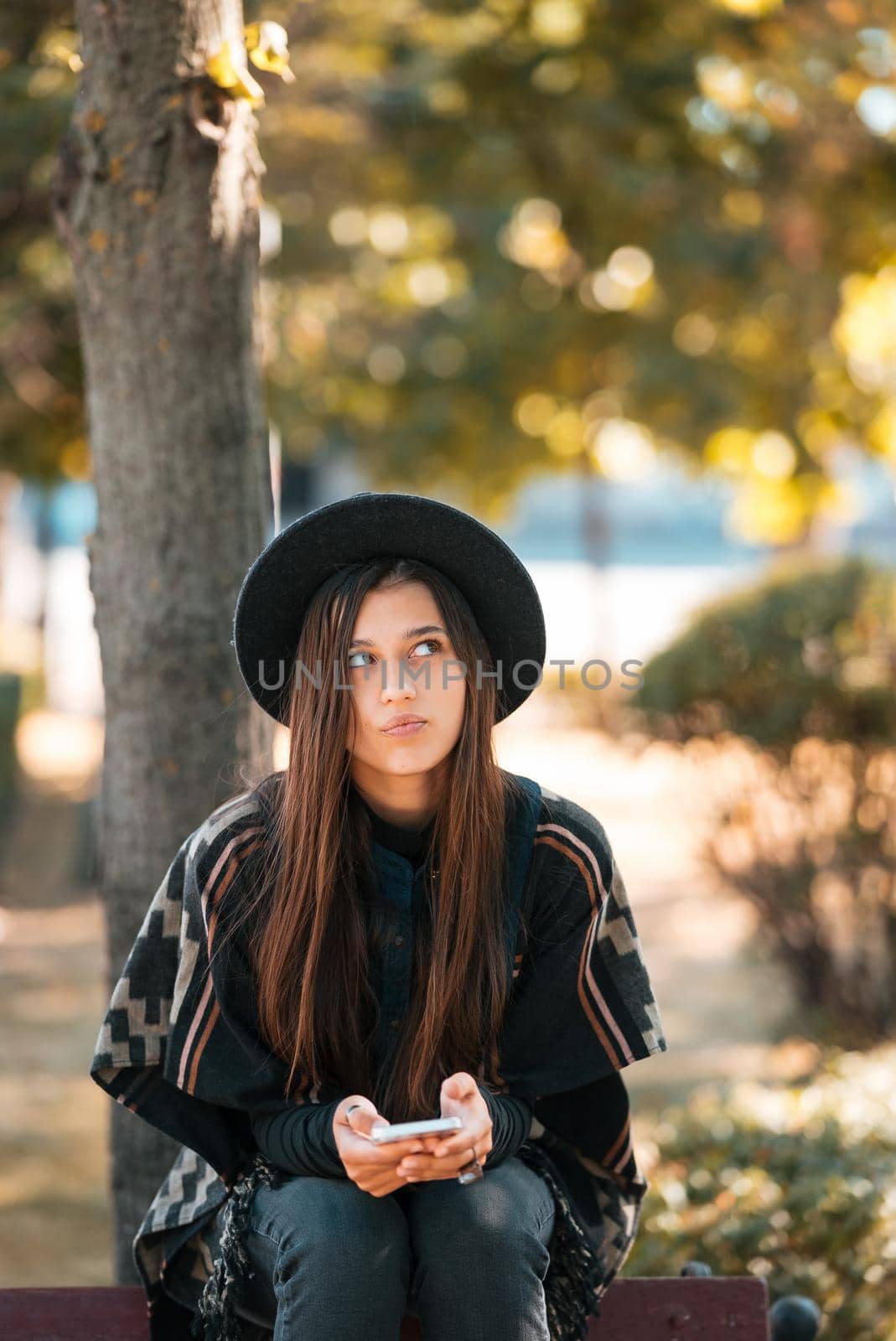 Young woman on a bench in the autumn park. People, freedom, lifestyle, travel and vacations concept.