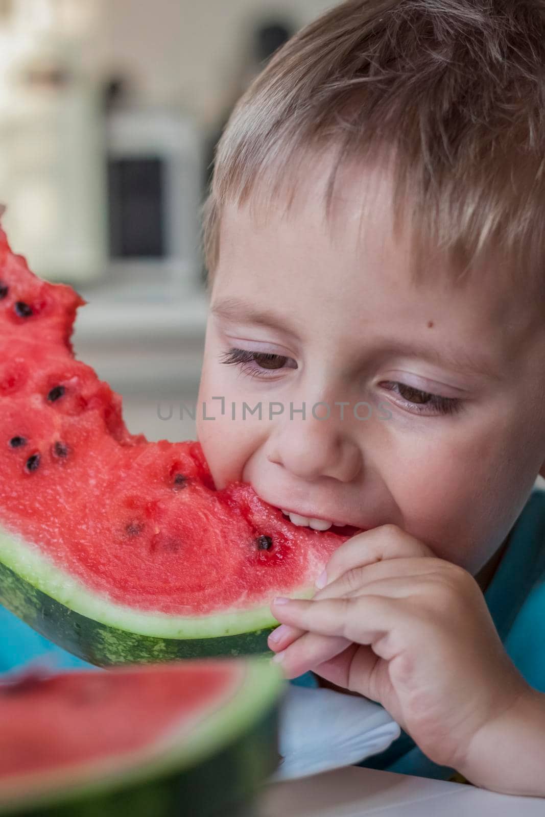 Cute boy eating watermelon at home. Real emotions without posing. children