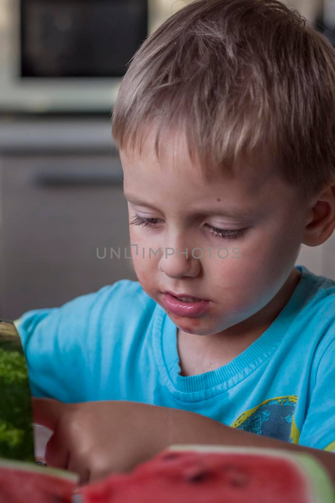 Cute boy eating watermelon at home. Real emotions without posing. children