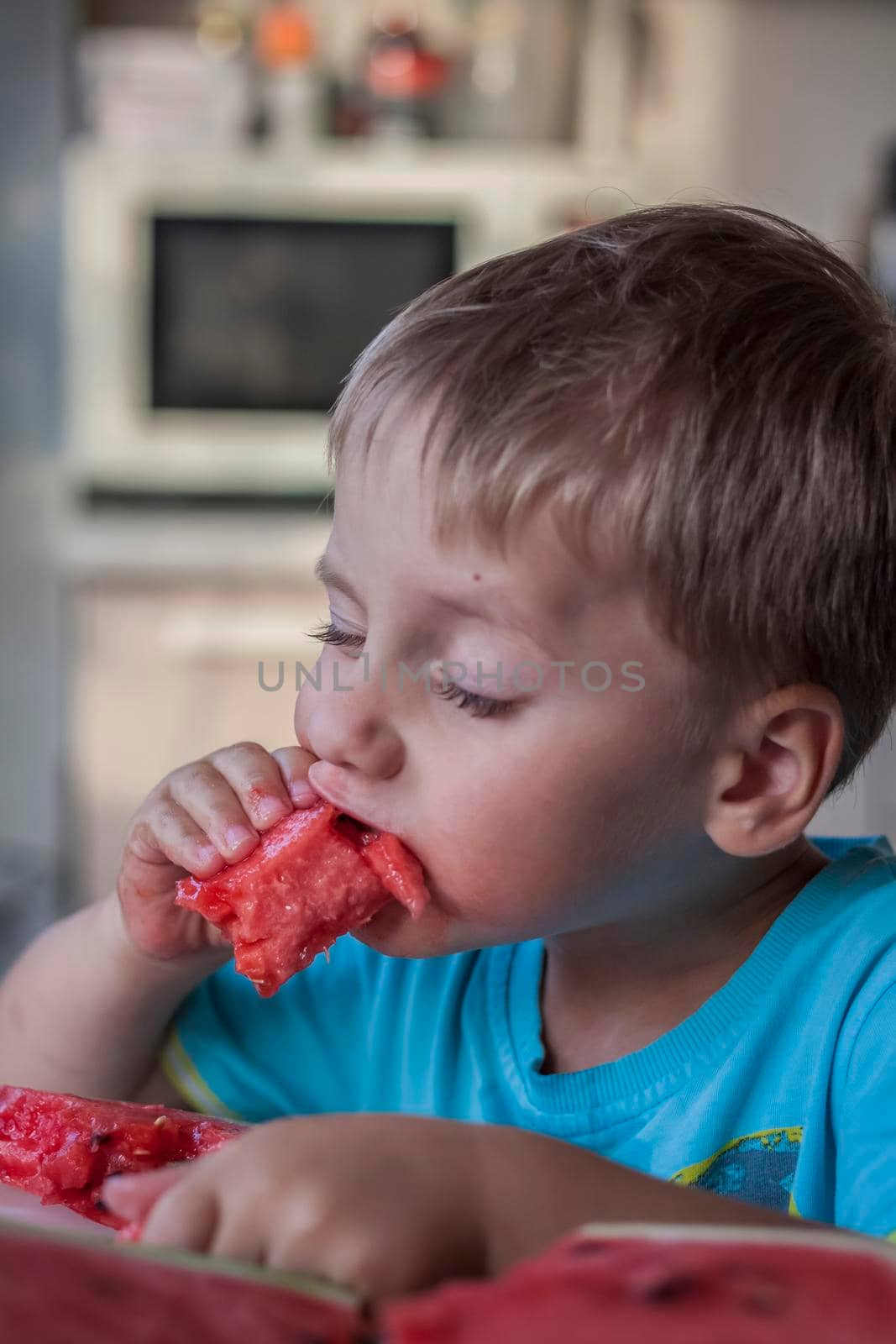 Cute boy eating watermelon at home. Real emotions without posing. children