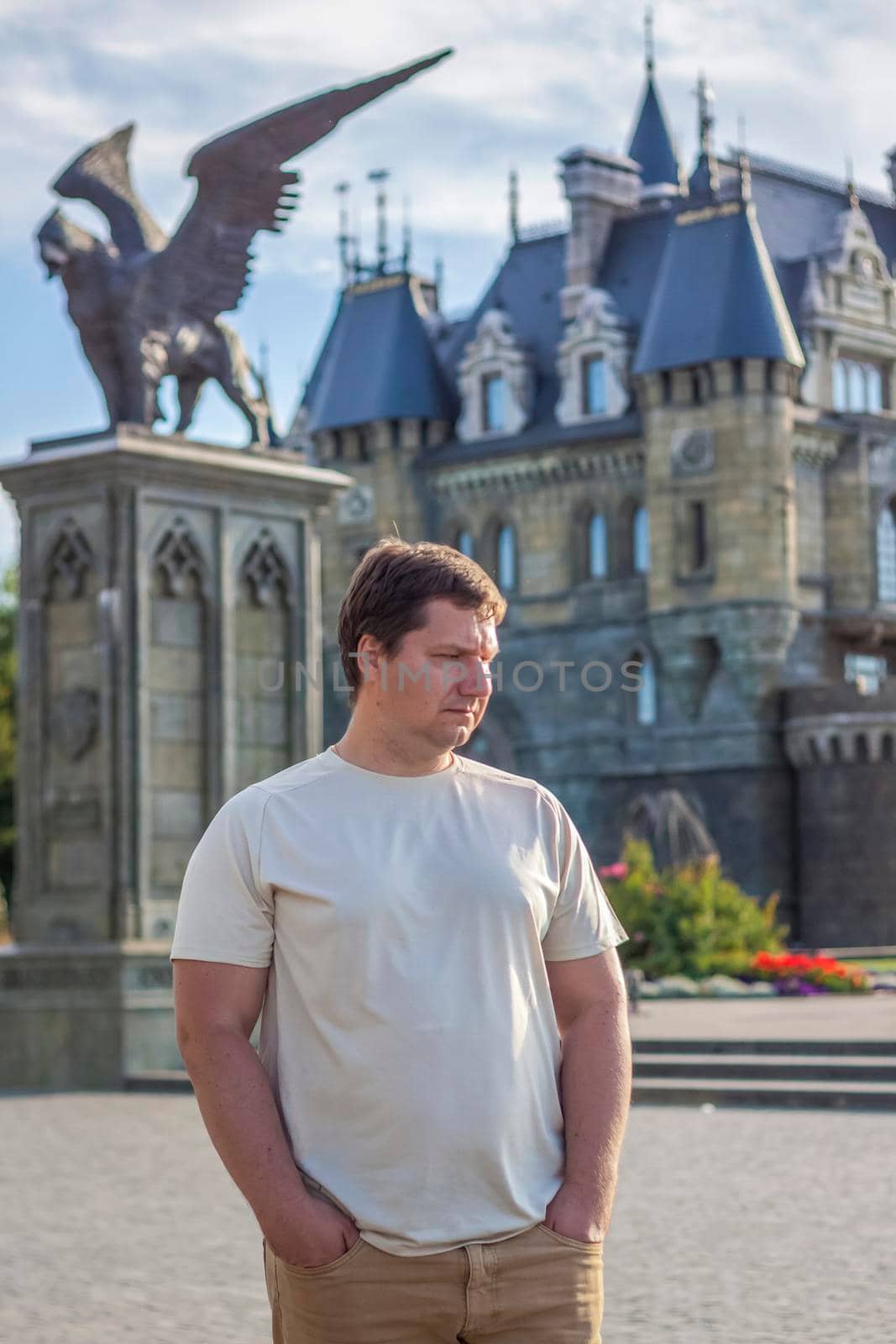 A man on the background of a Gothic-style castle. The territory of the tourist complex.