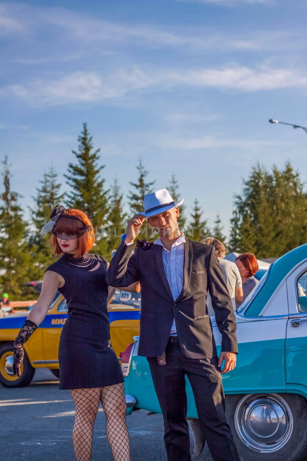 2022-08-12 Tatarstan, Verkhneuslonsky district, Savino village. Resort town "Sviyazhsky hills". Kazan Festival of Historical Cars. A man and a woman in retro clothes pose near cars