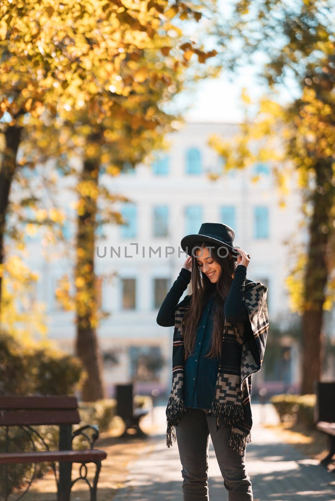 Stylish woman in poncho and hat enjoys autumn nature. People, freedom, lifestyle, travel and vacations concept.