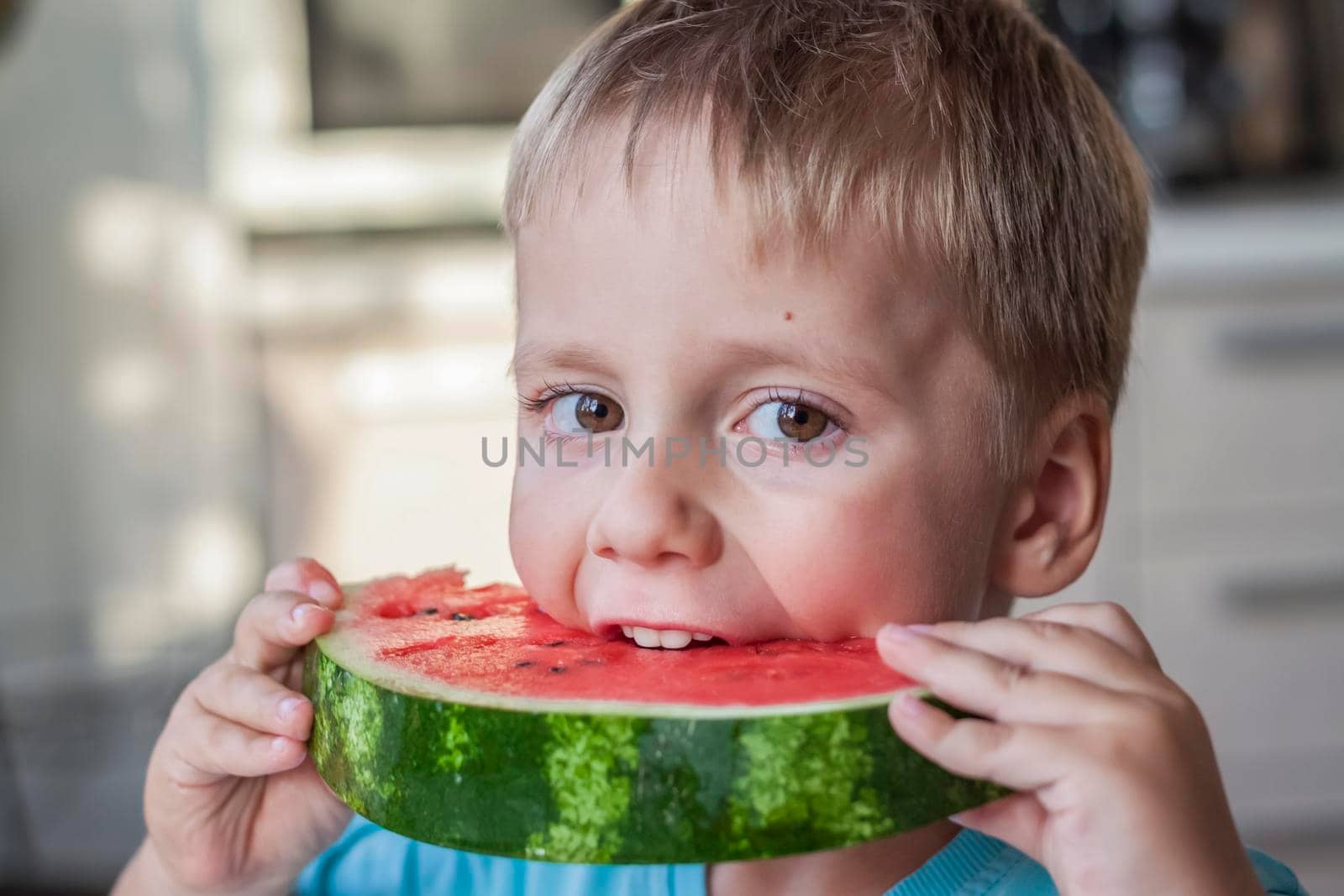 Cute boy eating watermelon at home. Real emotions without posing. children
