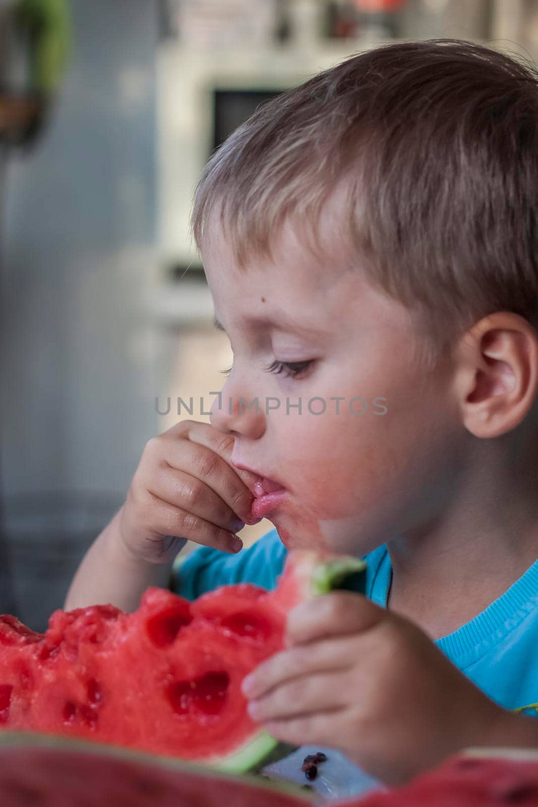 Cute boy eating watermelon at home. Real emotions without posing. children