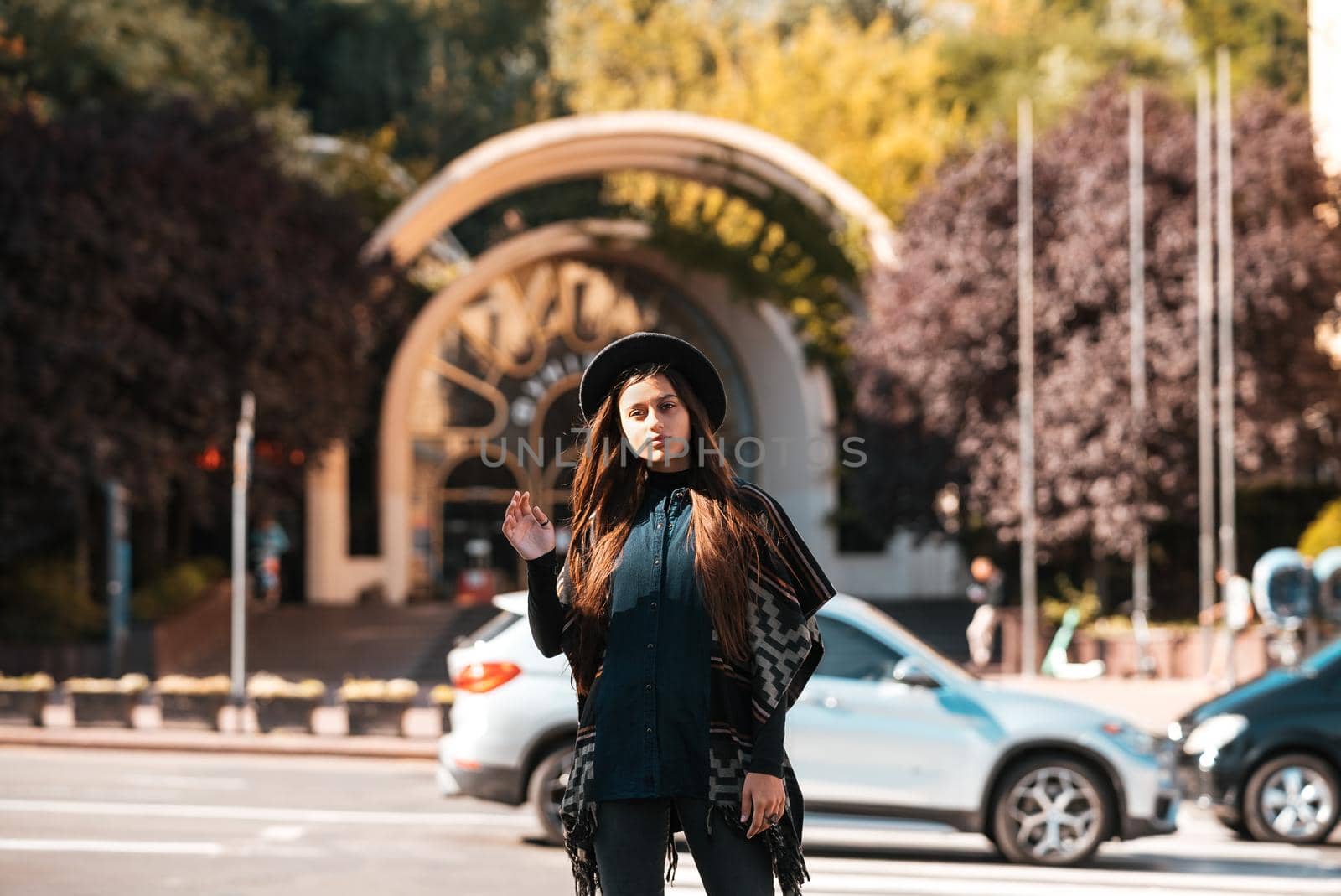 Beautiful fashionable woman in a hat and poncho at the city street