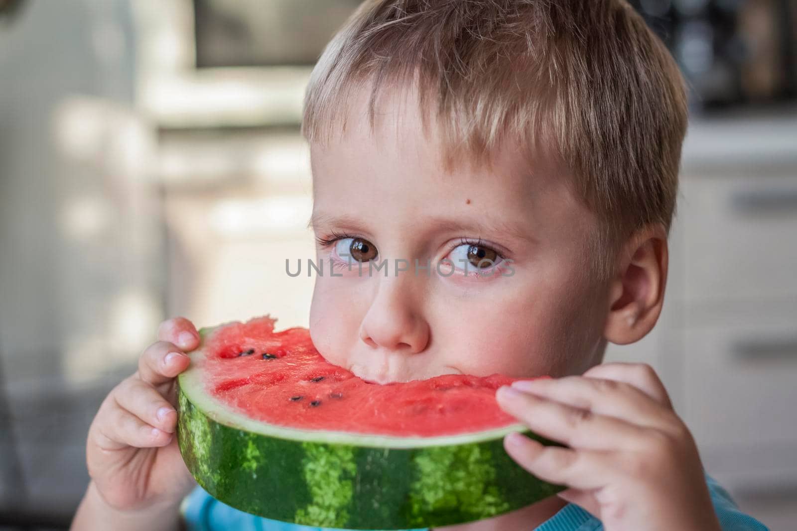 Cute boy eating watermelon at home. Real emotions without posing. children