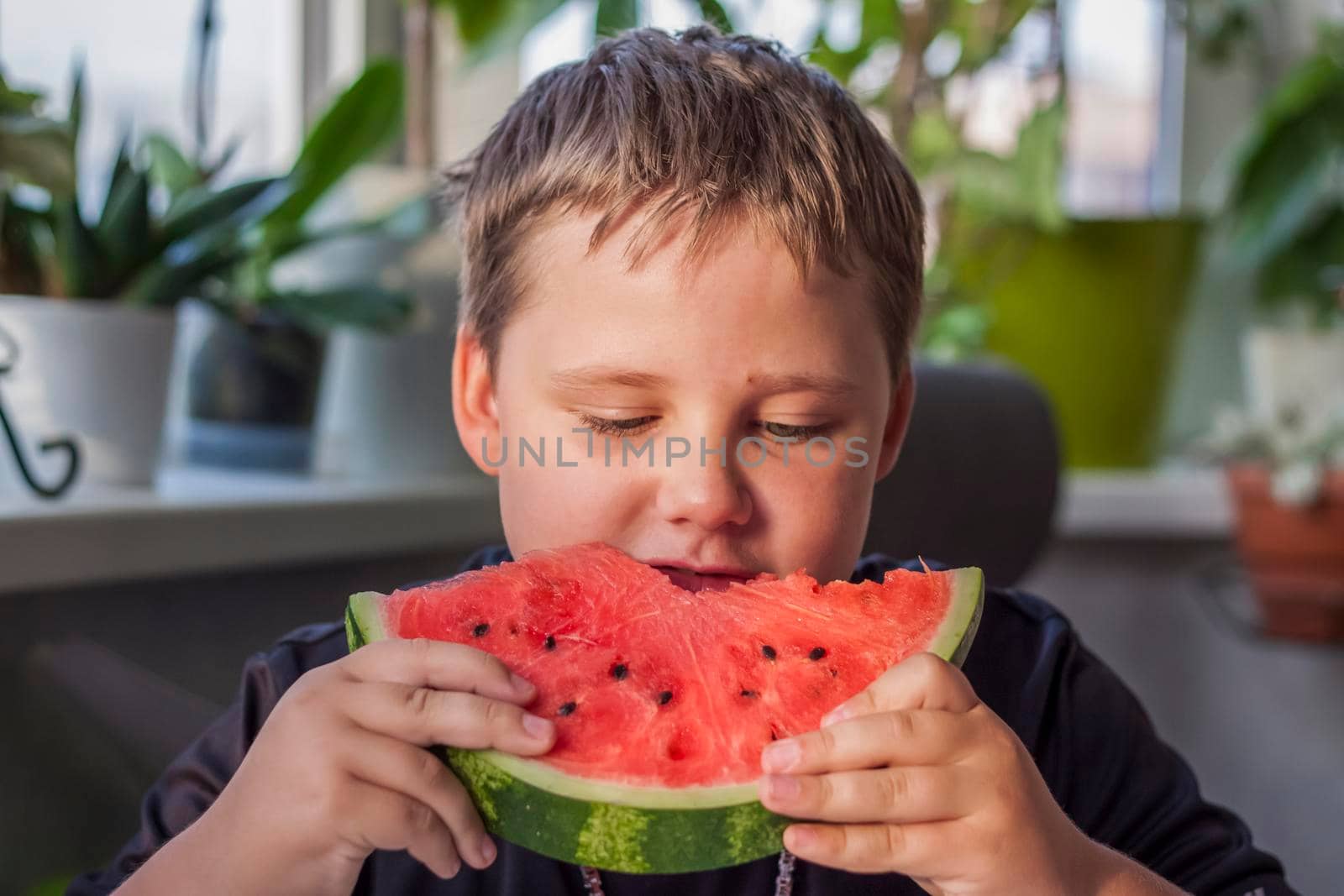 Cute boy eating watermelon at home. Real emotions without posing. children