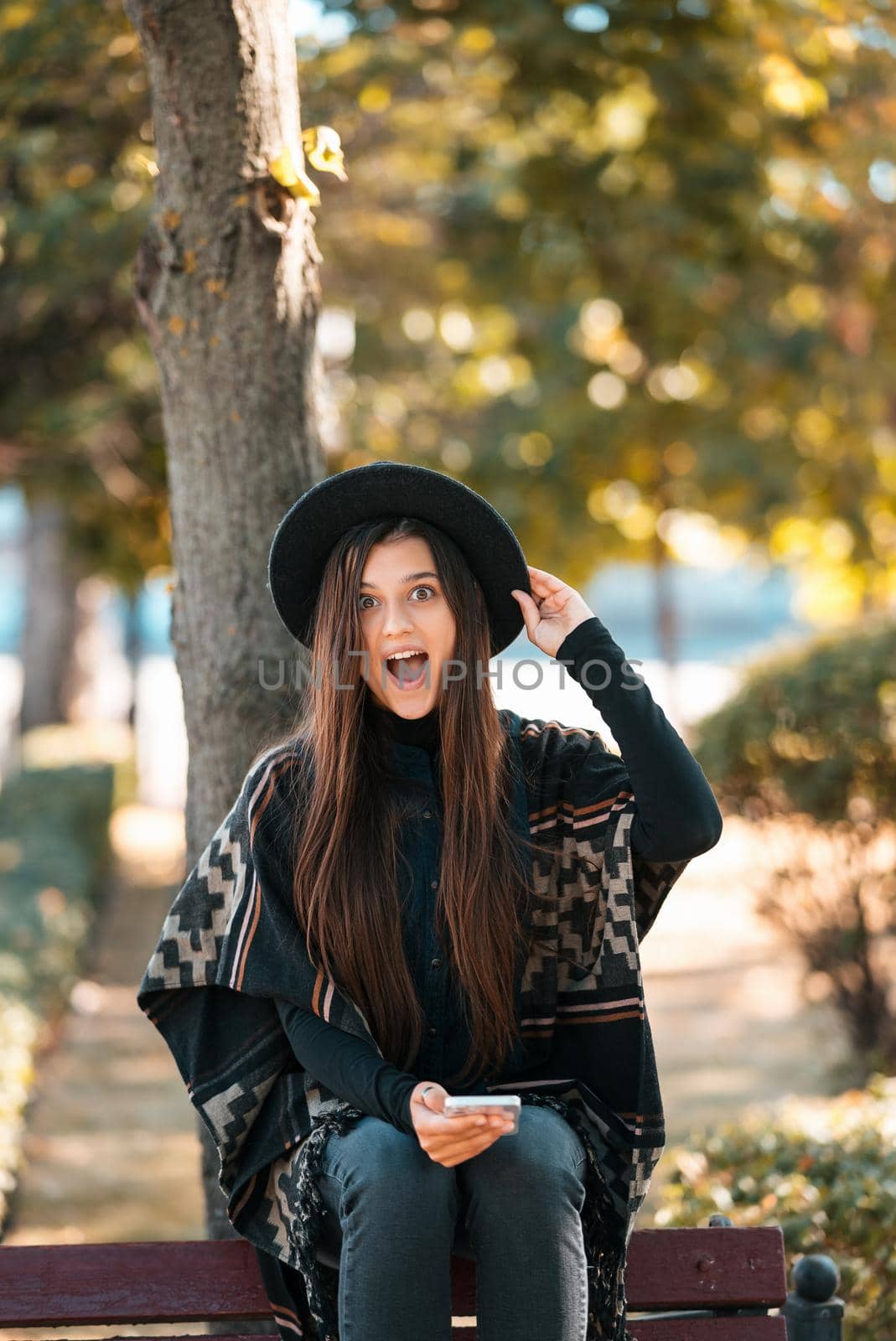 Young woman on a bench in the autumn park. People, freedom, lifestyle, travel and vacations concept.