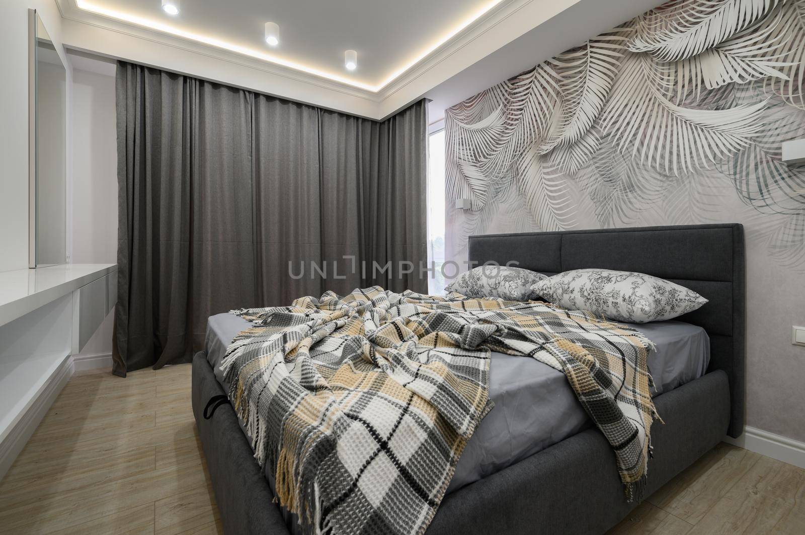 Stylish interior of gray bedroom with comfortable double bed