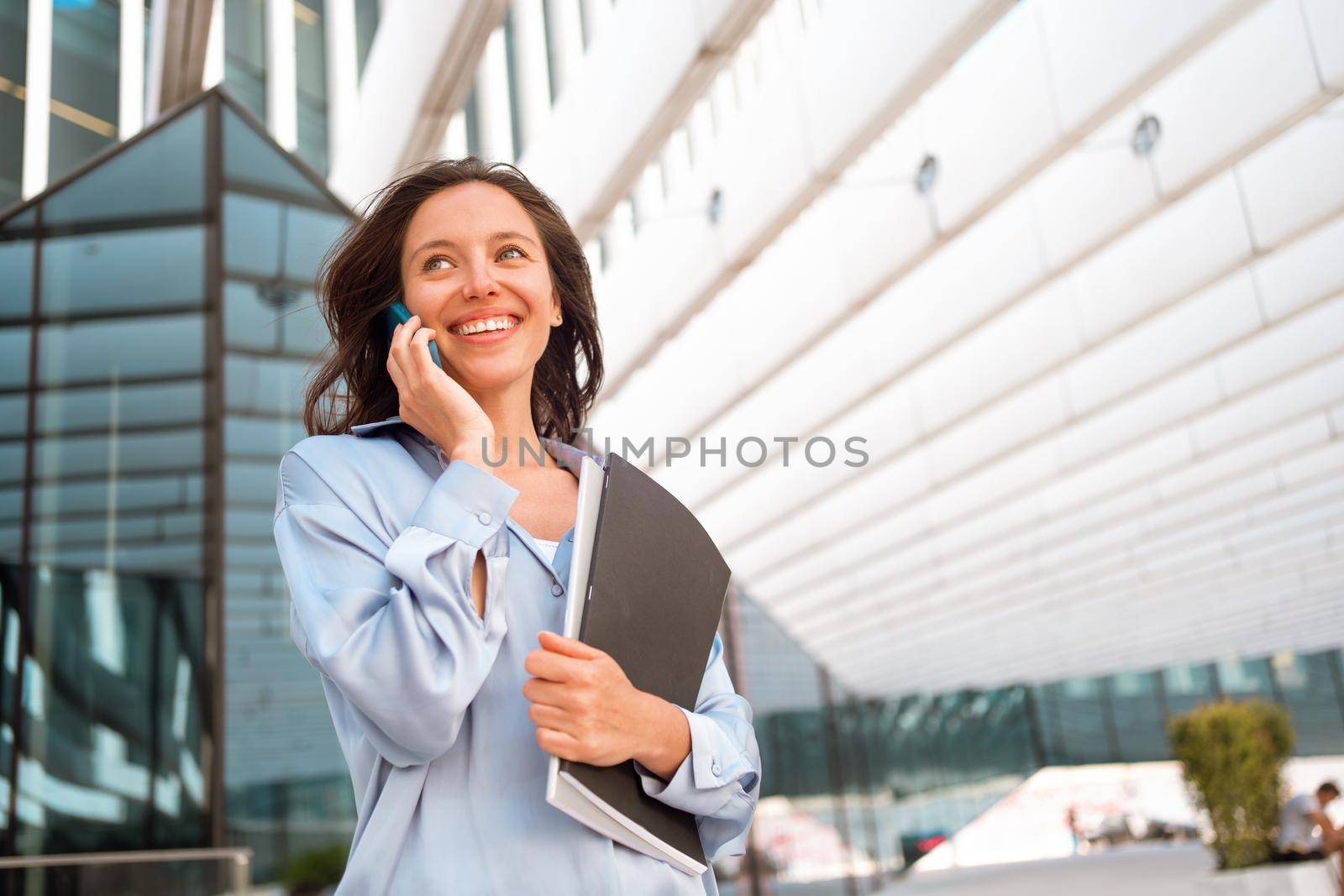 Excited caucasian businesswoman standing near office building have phone conversation feeling surprised Happy female worker happy smile after hear good news. positive cell phone conversation