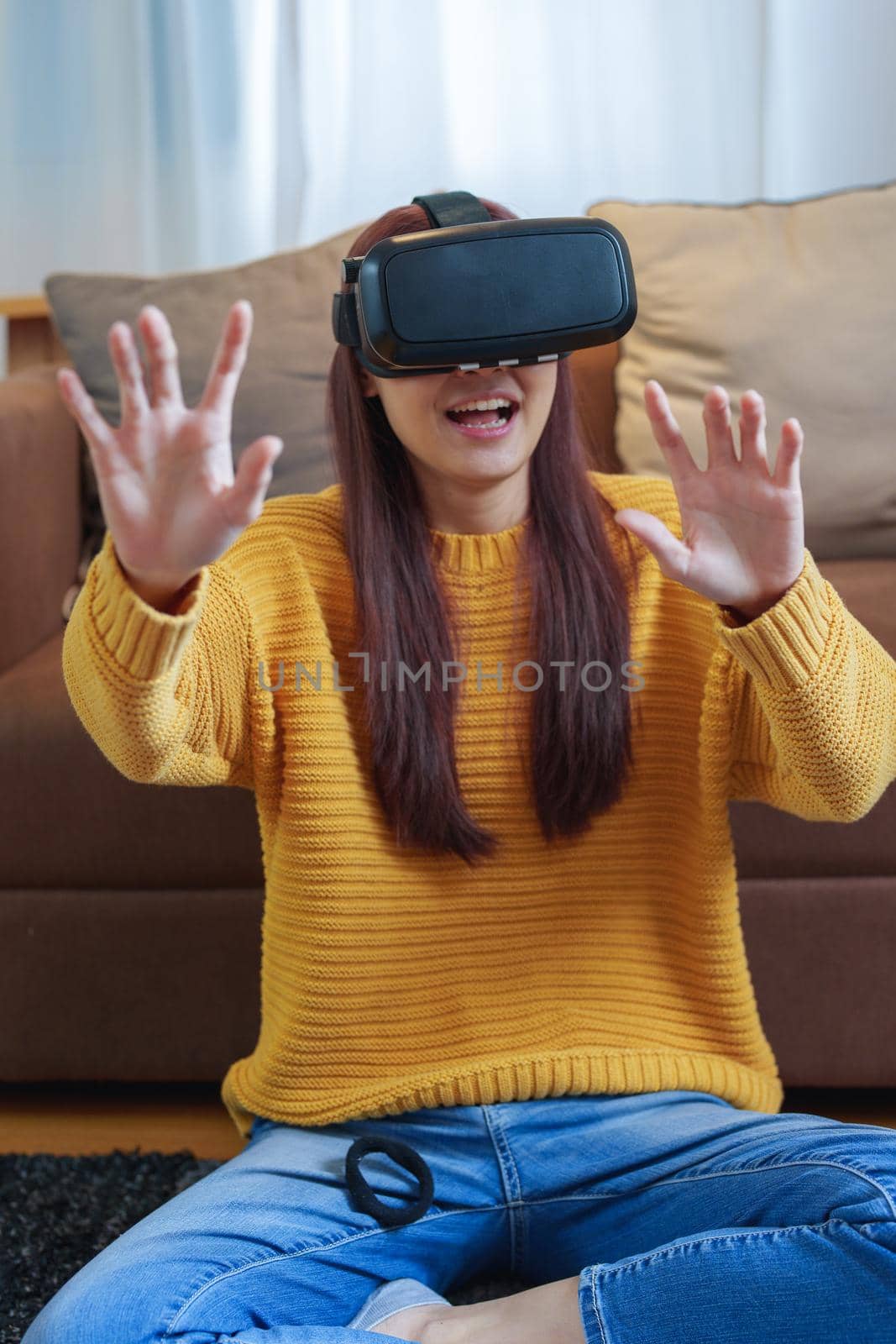 portrait of a young Asian woman using virtual reality simulator headset at home by Manastrong