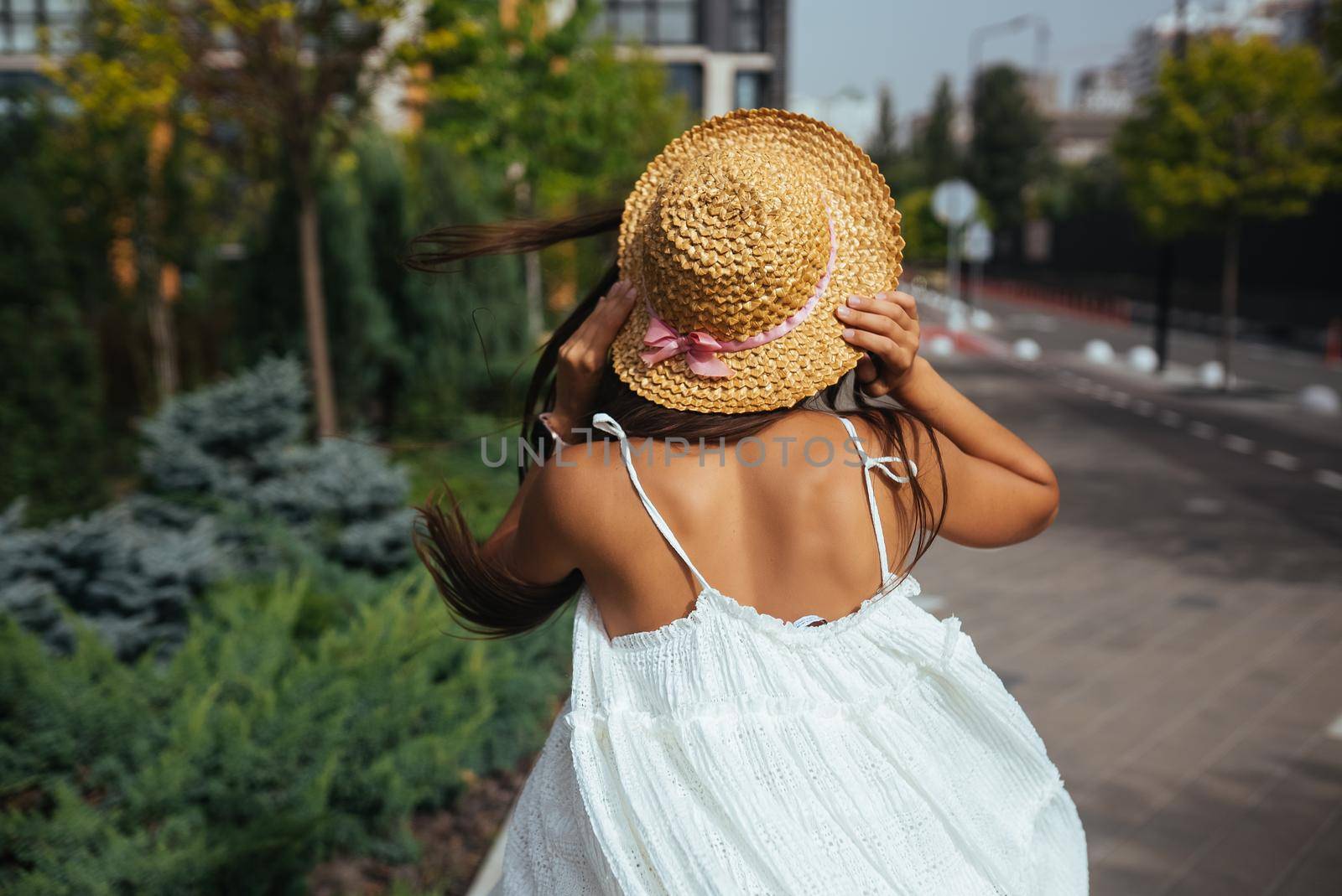 Young beautiful brunette woman in dress walking on the street, summer embankment outdoors