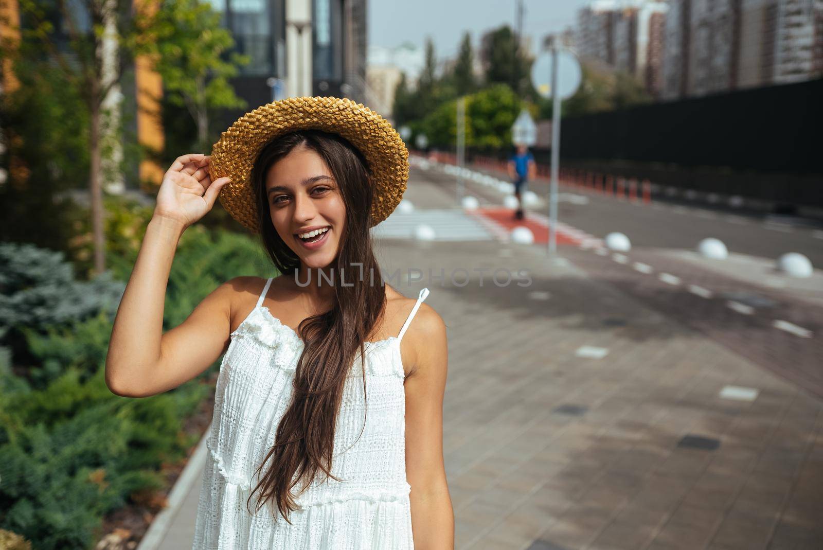 Young beautiful brunette woman in dress walking on the street, summer embankment outdoors