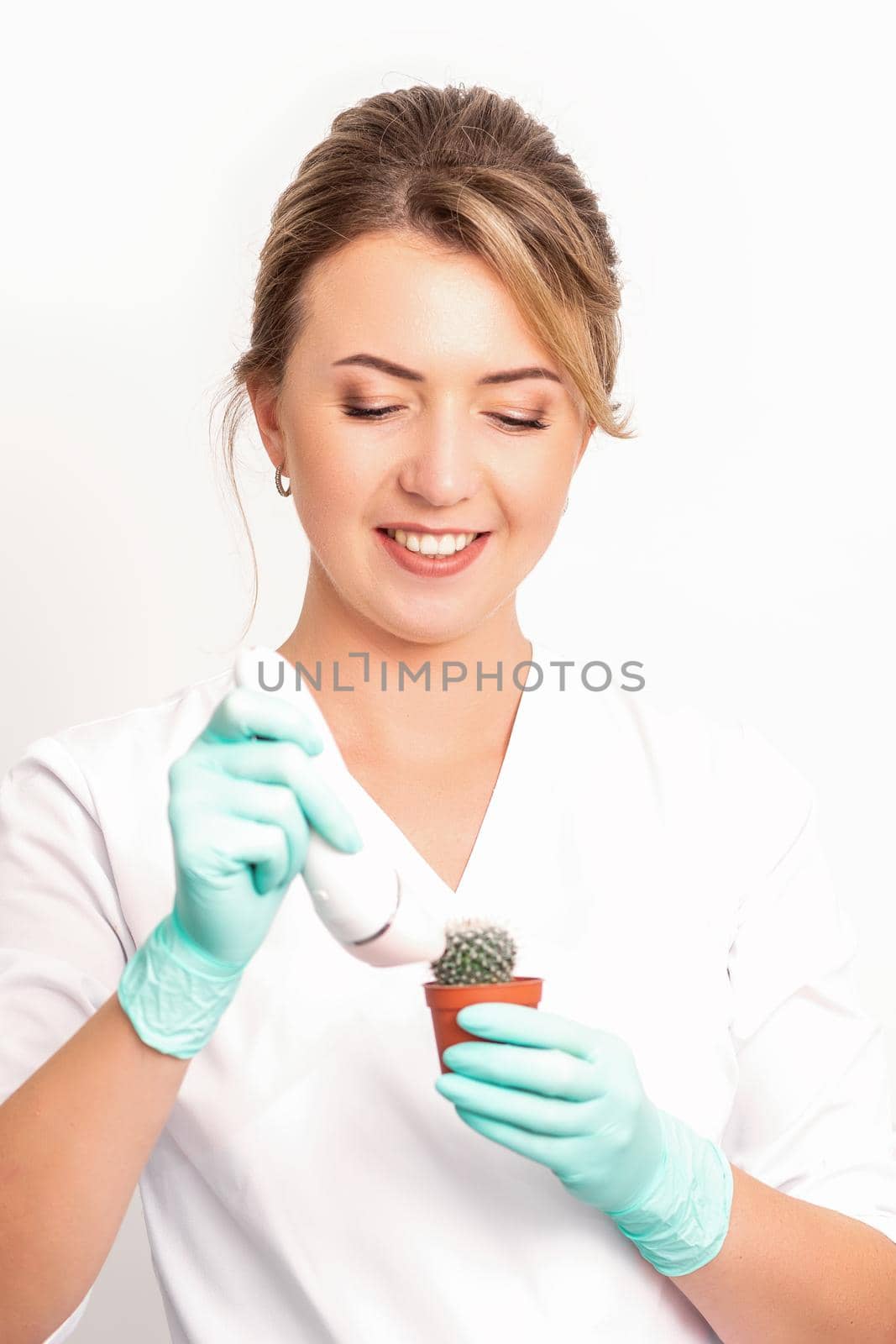 A smiling female beautician holds little green cactus with the razor in her hands. Hair removal concept