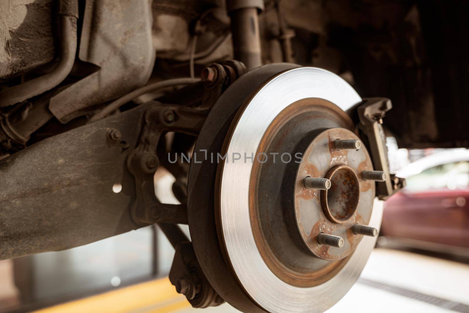 Car disc brake system. Car suspension in process of new tire replacement at garage workshop. Car disc brake mechanic check and repair. Disk break rotor. Car in change tire process at service station.