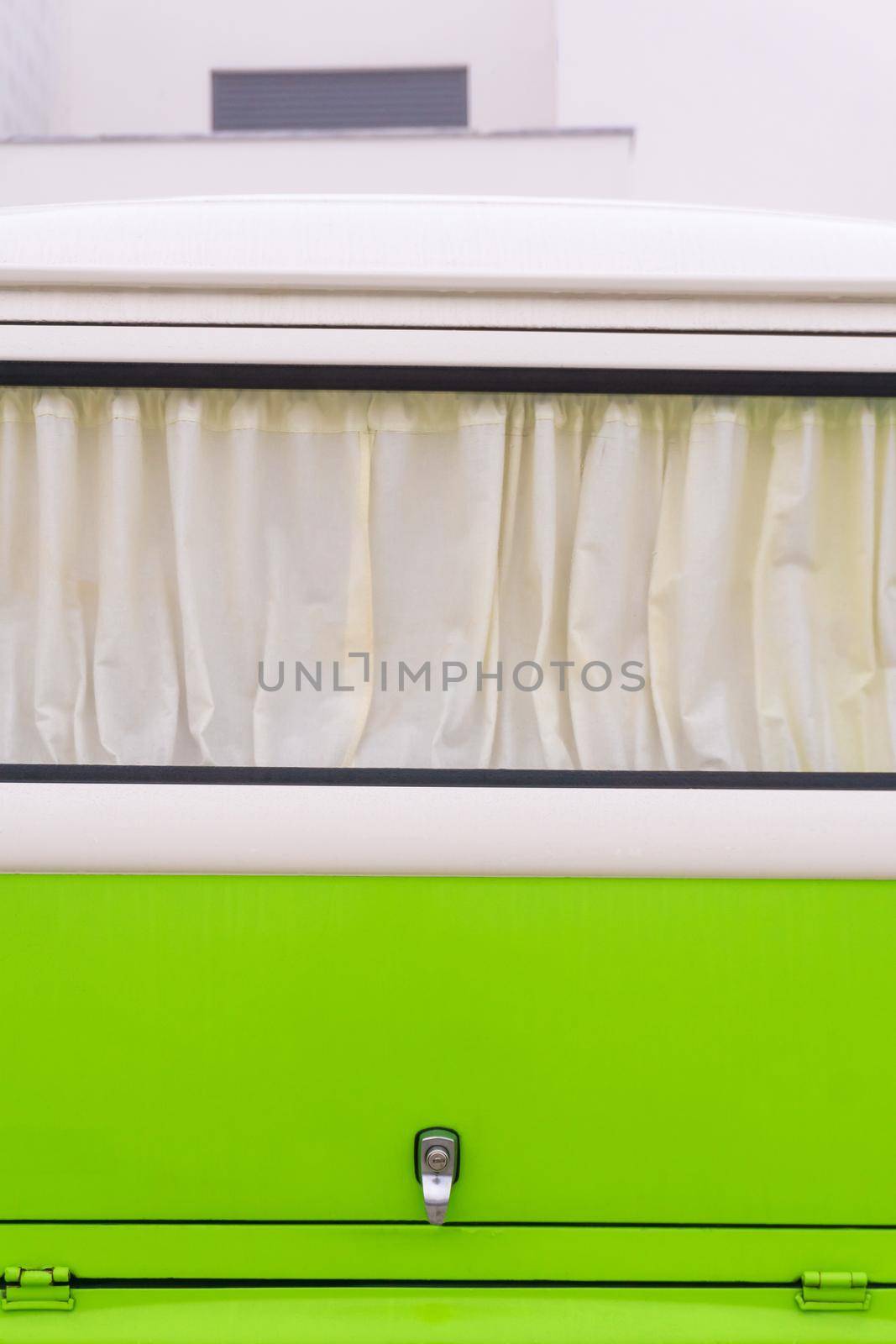 Curtained window of a bright white and green retro Volkswagen van close up