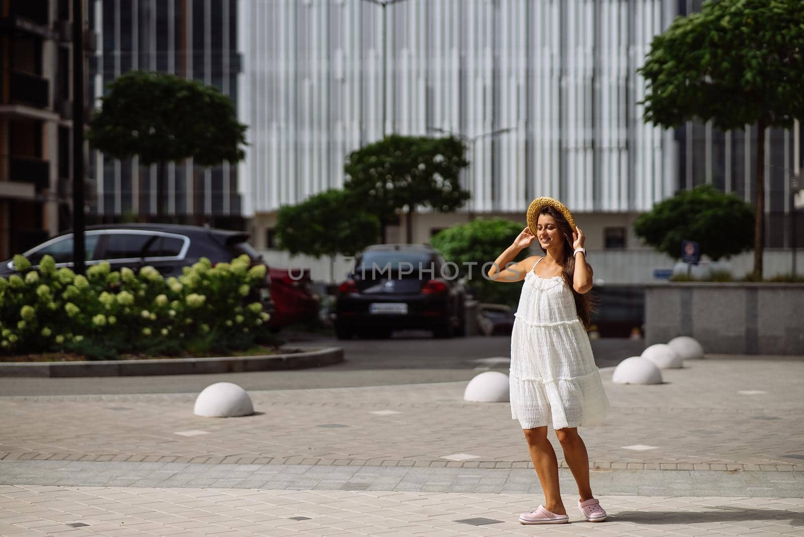 Young sexy beautiful pretty woman in white dress walking at city street