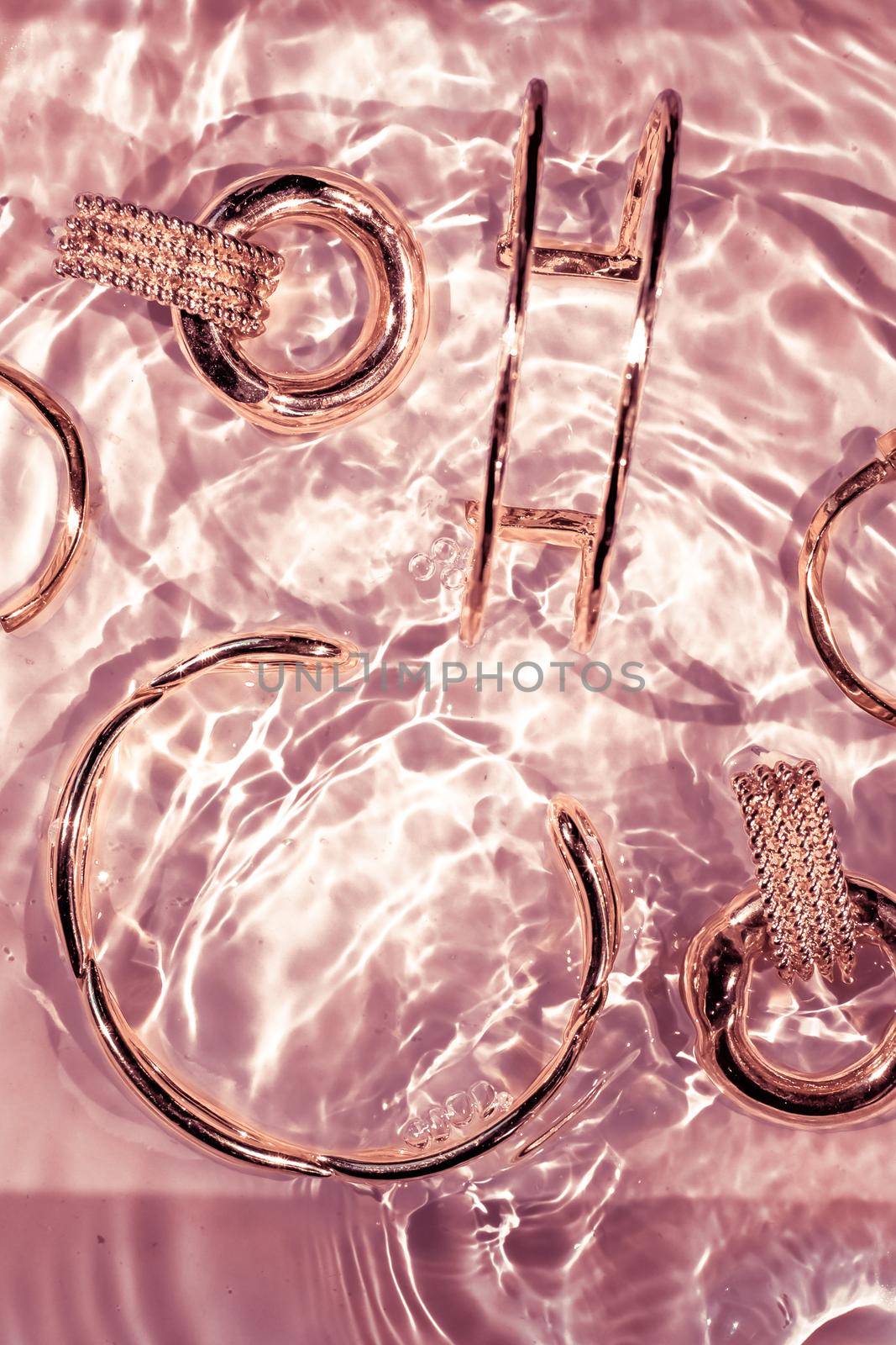 Jewellery branding, fashion gift and luxe shopping concept - Rose gold bracelets, earrings, rings, jewelery on pink water background, luxury glamour and holiday beauty design for jewelry brand ads