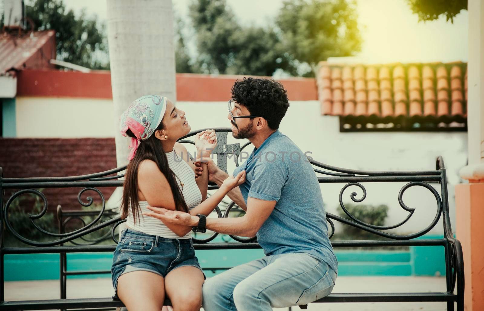 Man arguing with girlfriend sitting in a park. Young couple arguing sitting on a park bench, Concept of aggressive couples in the park. Upset couple arguing on a park bench