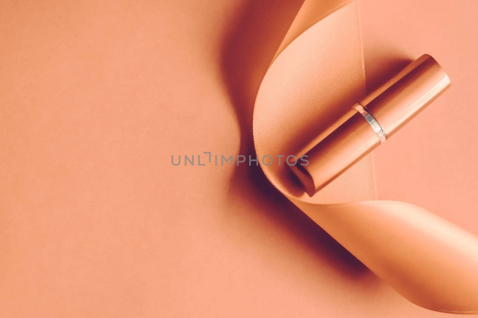 Cosmetic branding, glamour lip gloss and shopping sale concept - Luxury lipstick and silk ribbon on orange holiday background, make-up and cosmetics flatlay for beauty brand product design