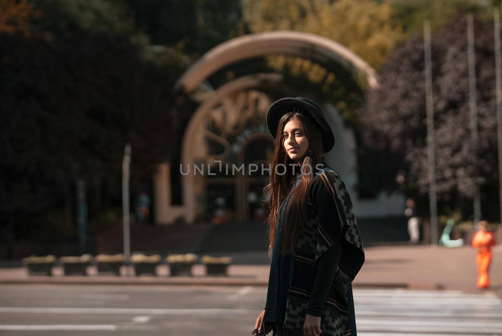 Beautiful fashionable woman in a hat and poncho at the city street