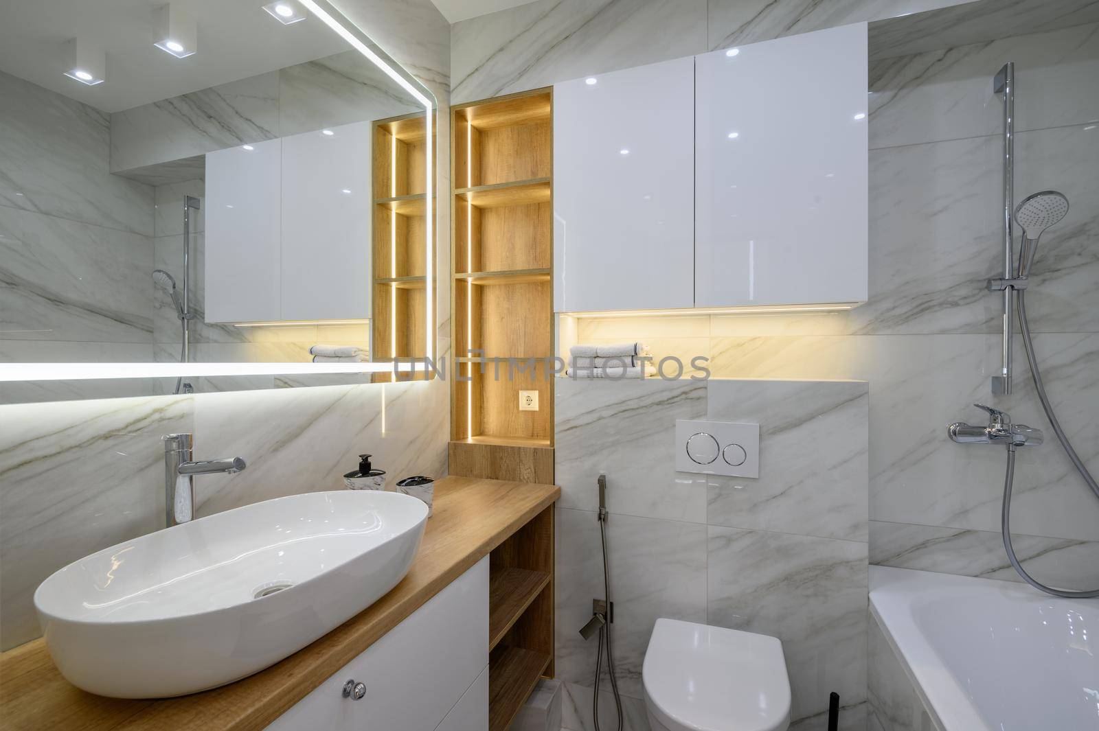 Luxury bathroom interior with marble tiles on the walls and a large mirror