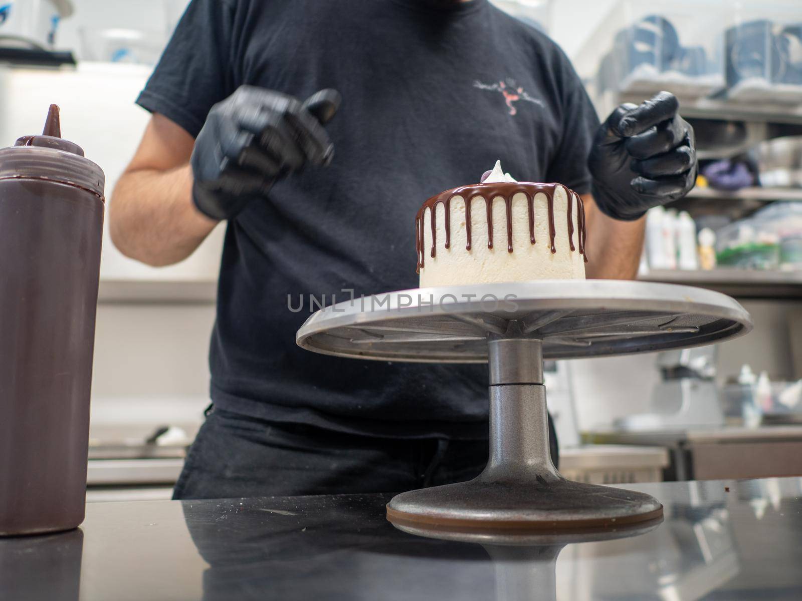unrecognizable worker preparing a sweet dripping choco cake and berries