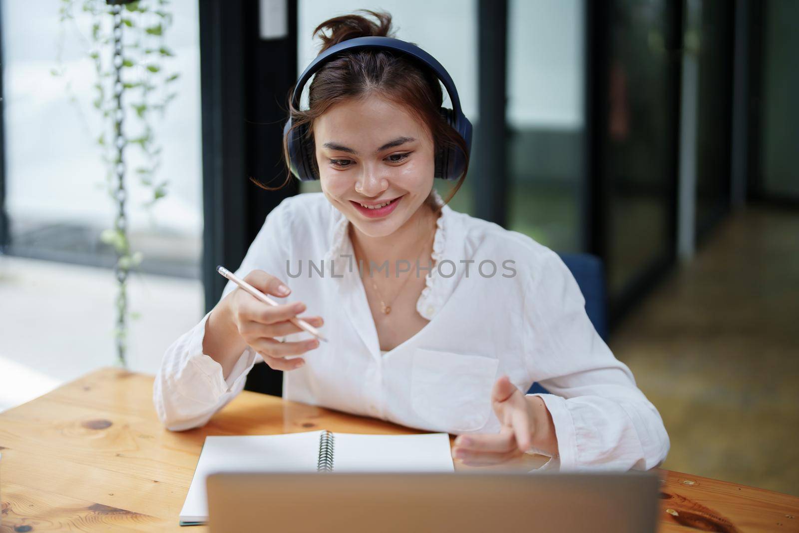 woman using a computer and earphone during a video conference by Manastrong