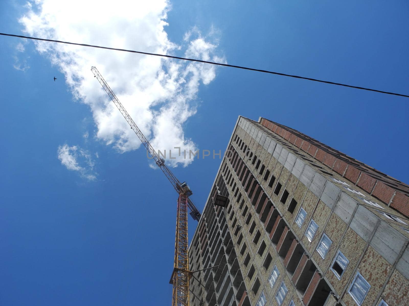 Crane and building under construction against blue sky.