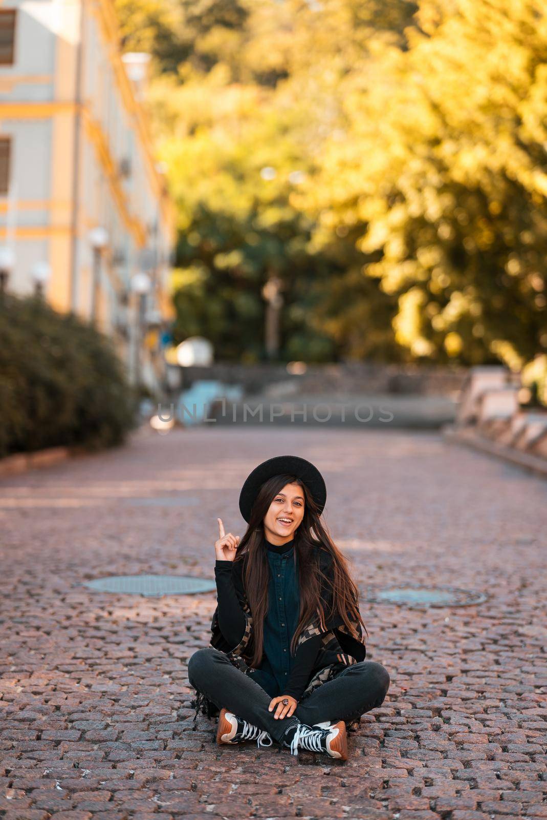 Young woman sitting at city show finger up, new idea, warm autumn day