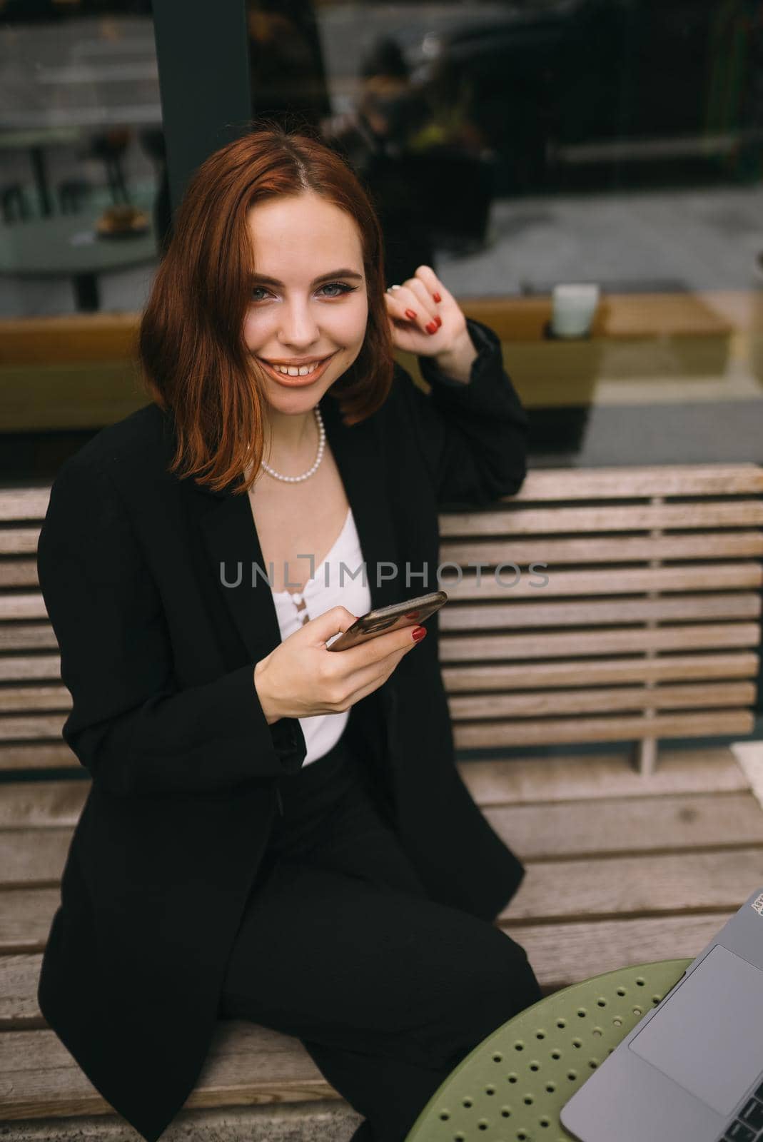 Attractive brunette woman at the street cafe reading a text messageon a phone.
