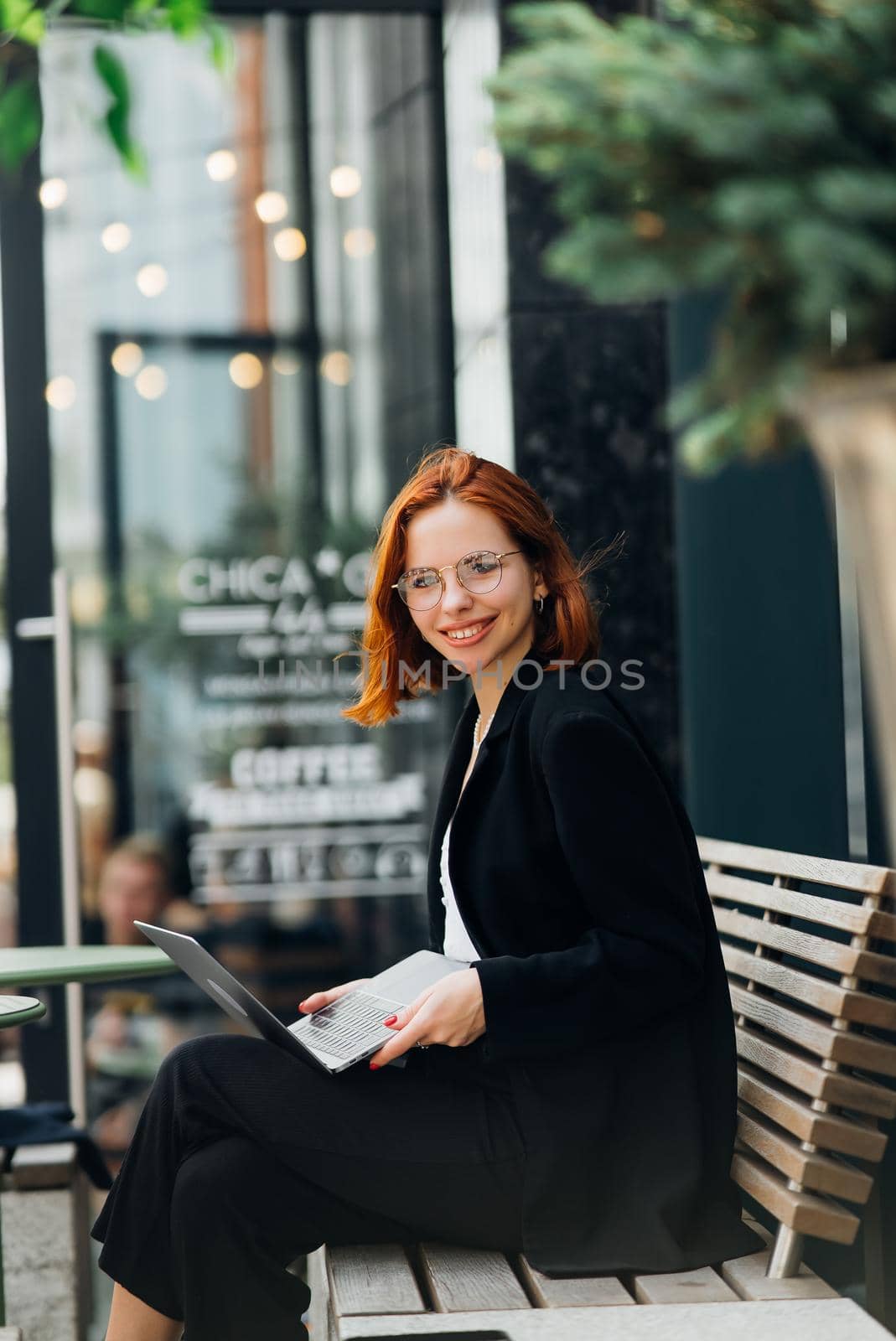 Beautiful redhead woman working on laptop at outdoors cafe