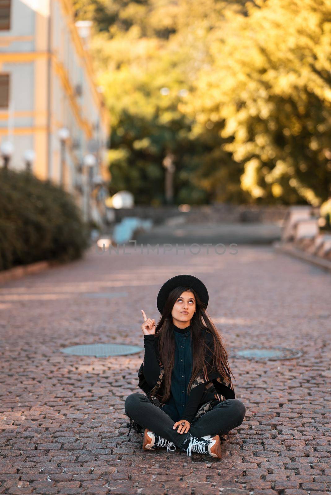 Young woman sitting at city show finger up, new idea, warm autumn day