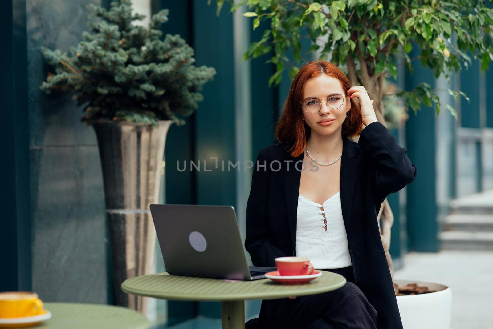 Happy young woman in a street cafe looks into the camera